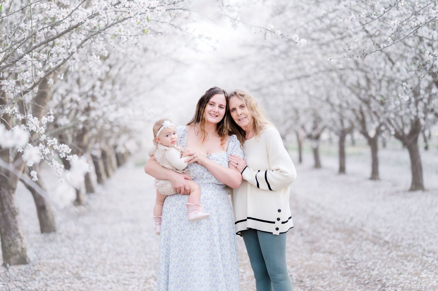 Family poses together in a snowy almond orchard during a winter photo session in California.