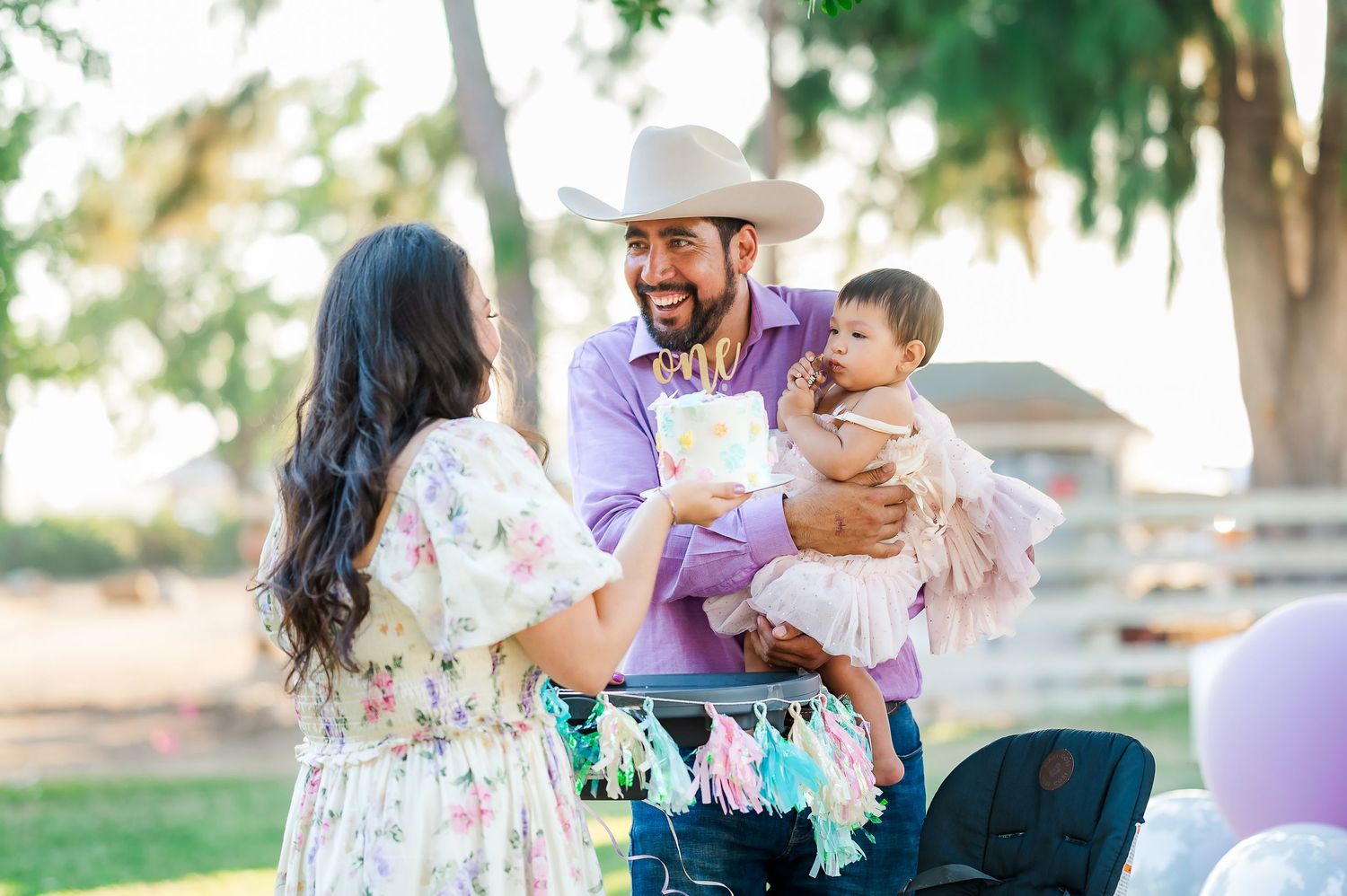 A family gathering outdoors with balloons and decorations in a park setting.