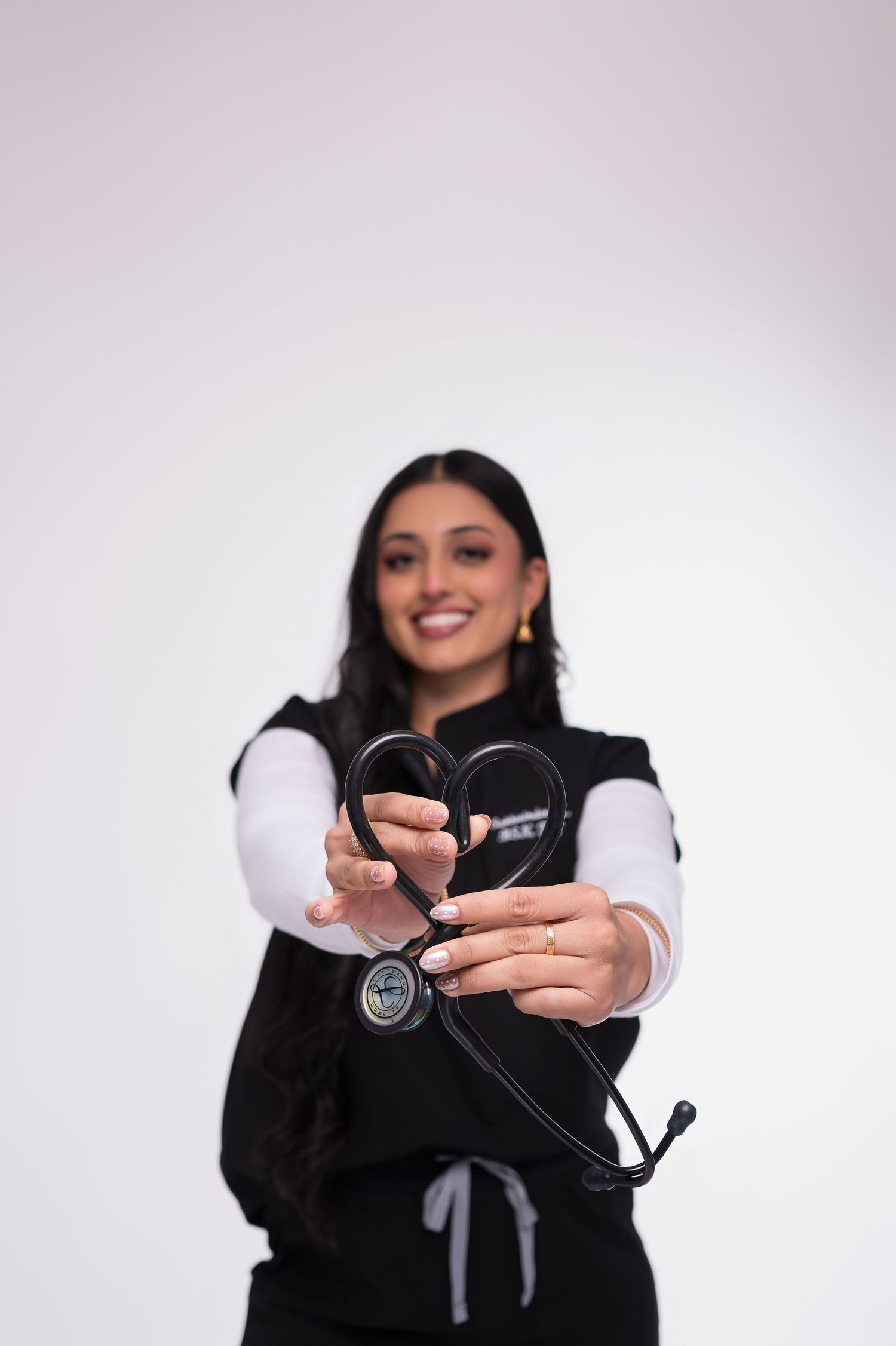 A person wearing a black vest holds and displays a pair of sunglasses against a white background.