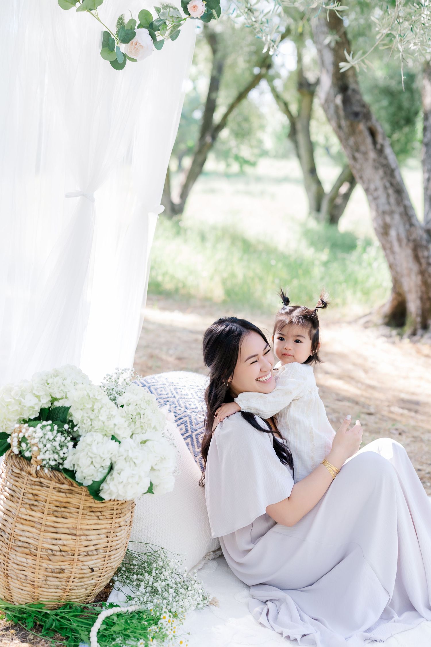 A dreamy outdoor photoshoot in a garden setting with white hydrangeas in wicker baskets and soft natural lighting.
