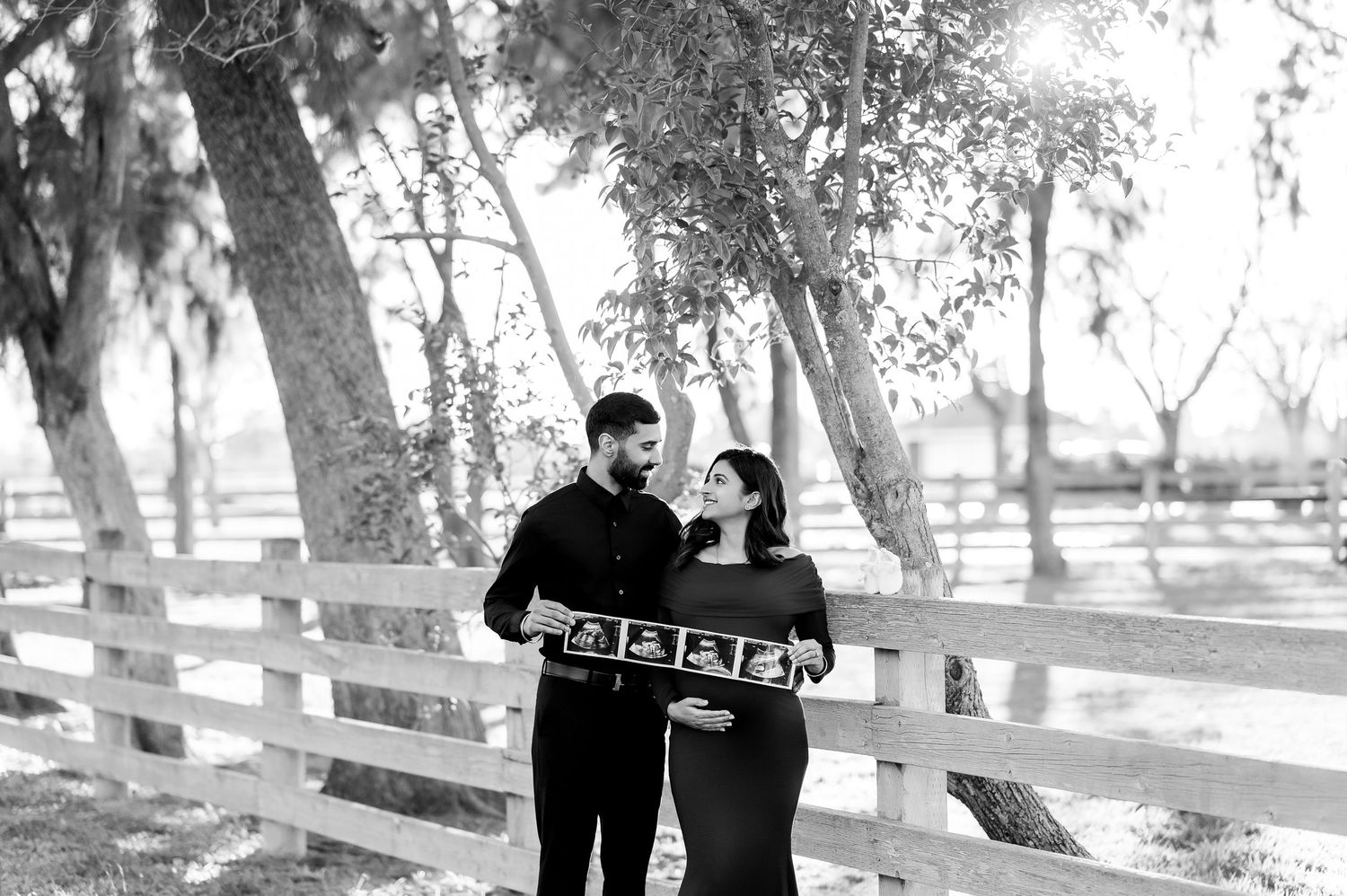 Black and white maternity photos captured in a serene outdoor setting with trees.