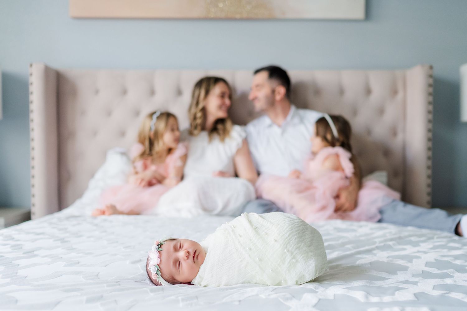 A collection of intimate family photos shows tender moments between parents and children on a cozy white bed.