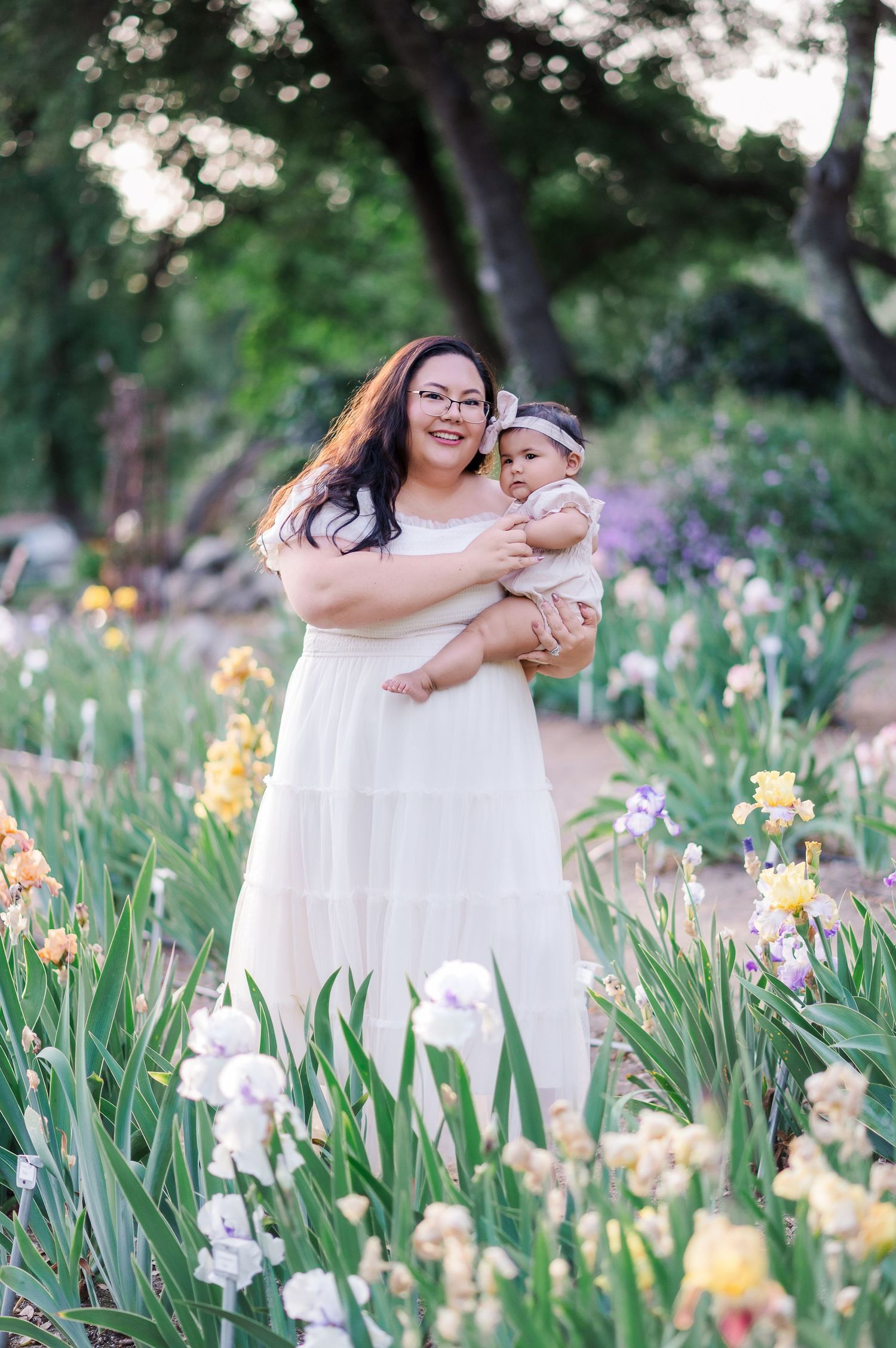 A tender moment captured in a garden filled with blooming yellow and purple irises on a sunny spring day.