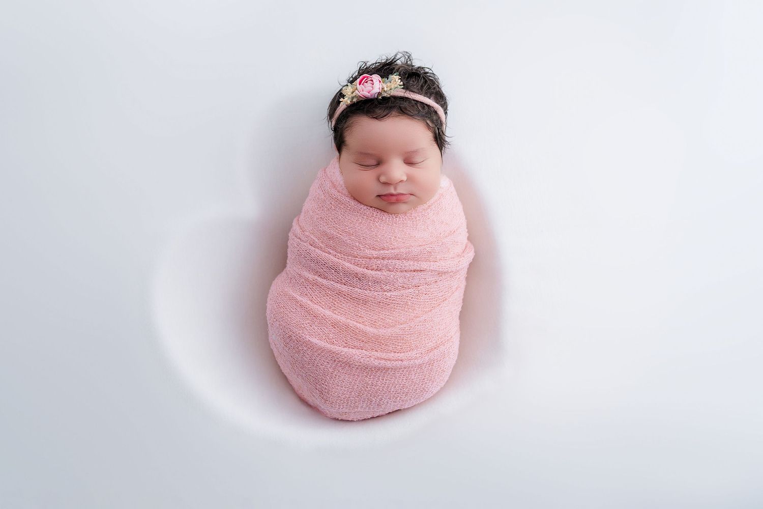 Newborn baby wrapped in soft pink blanket shown in four sequential photos getting progressively smaller.