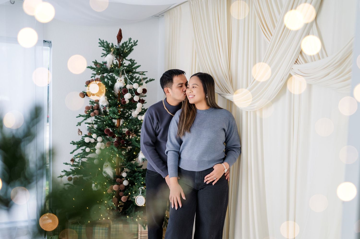 A romantic winter wedding photoshoot with white curtains, string lights, and evergreen decorations creating a cozy atmosphere.
