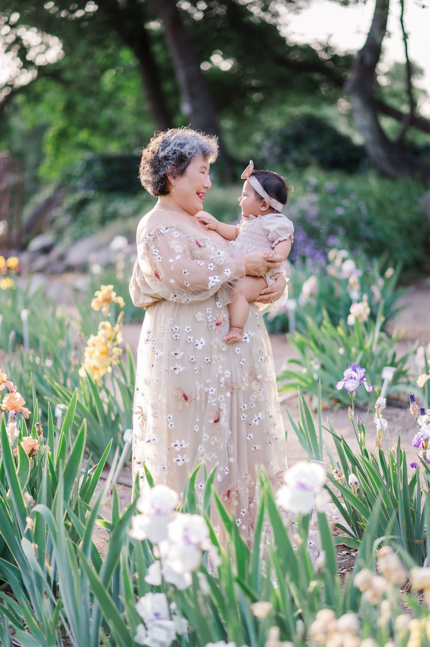A couple in matching floral dresses embraces in a blooming iris garden during springtime.