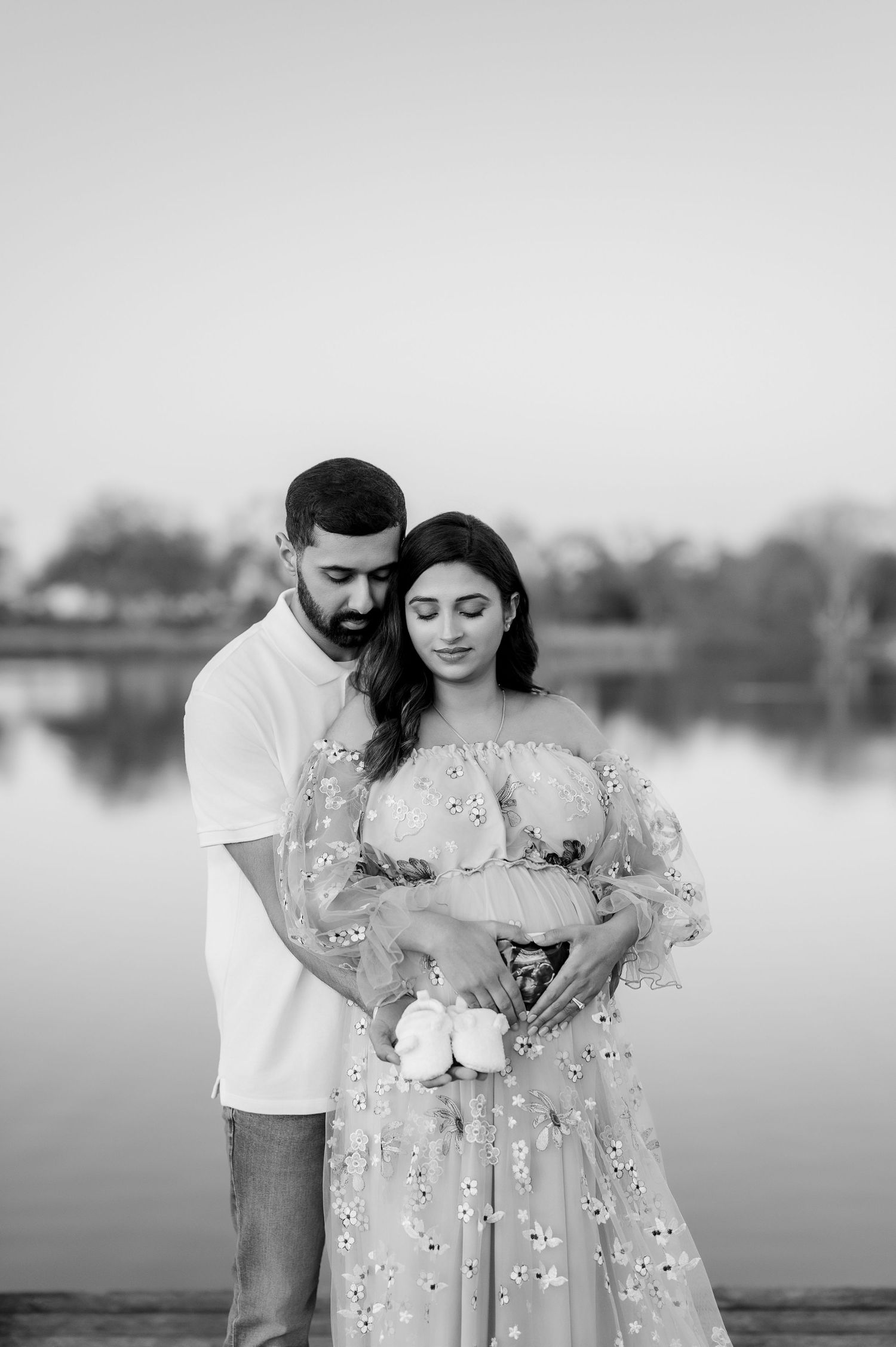 Black and white intimate maternity portrait by a serene lake.