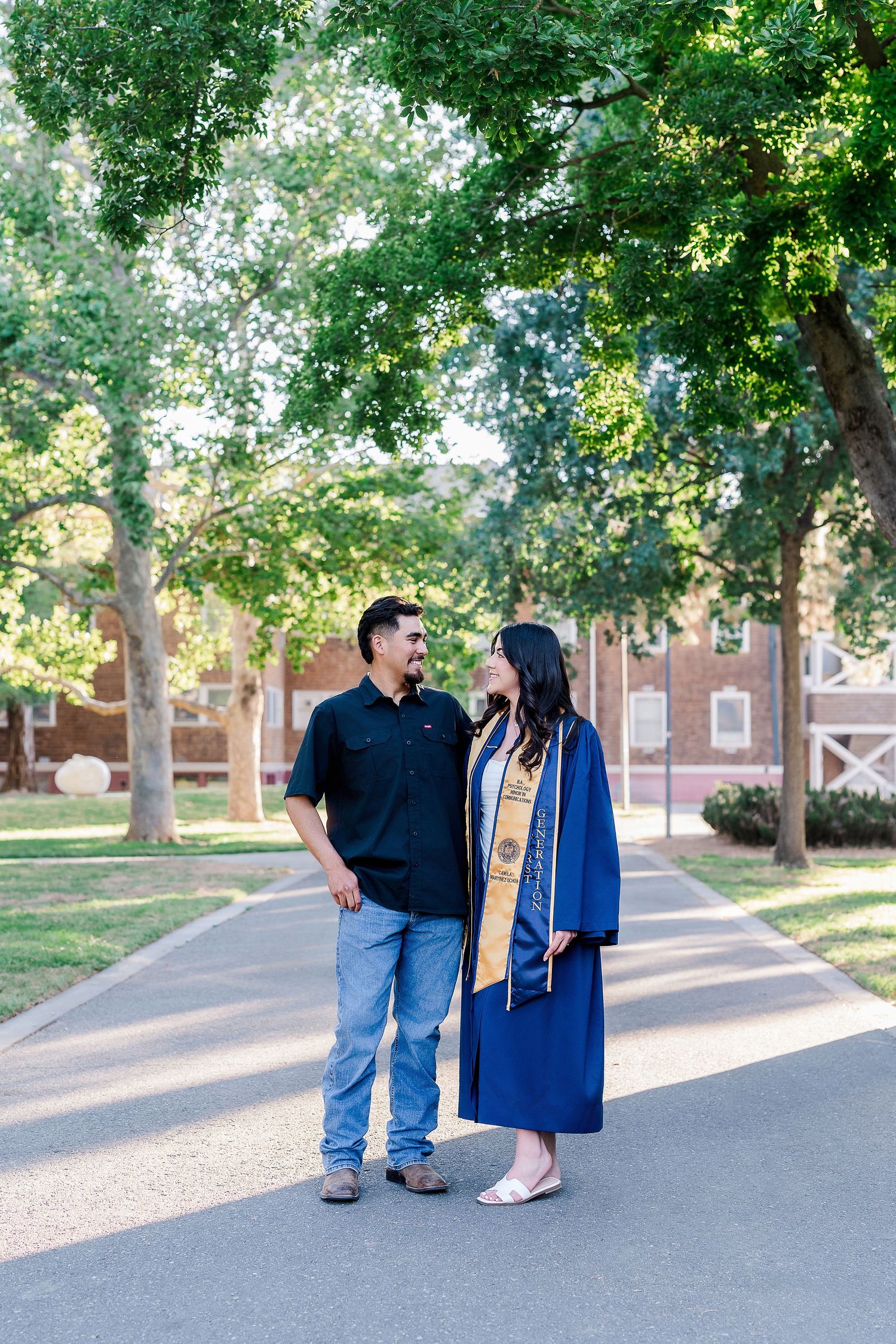 Family graduation portraits taken on tree-lined campus pathway during golden hour.