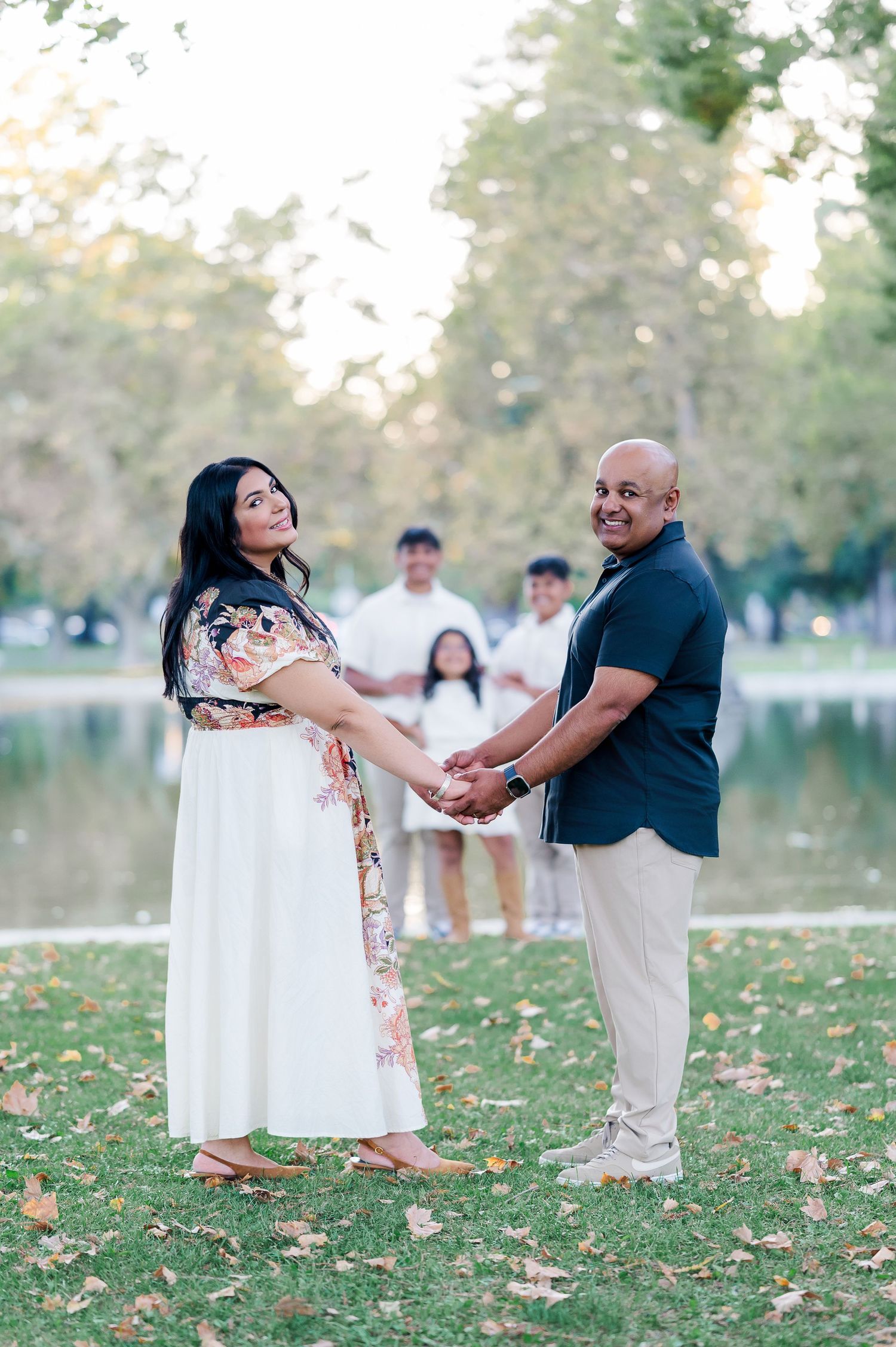 A couple dances together on grass during a romantic outdoor photoshoot at sunset.