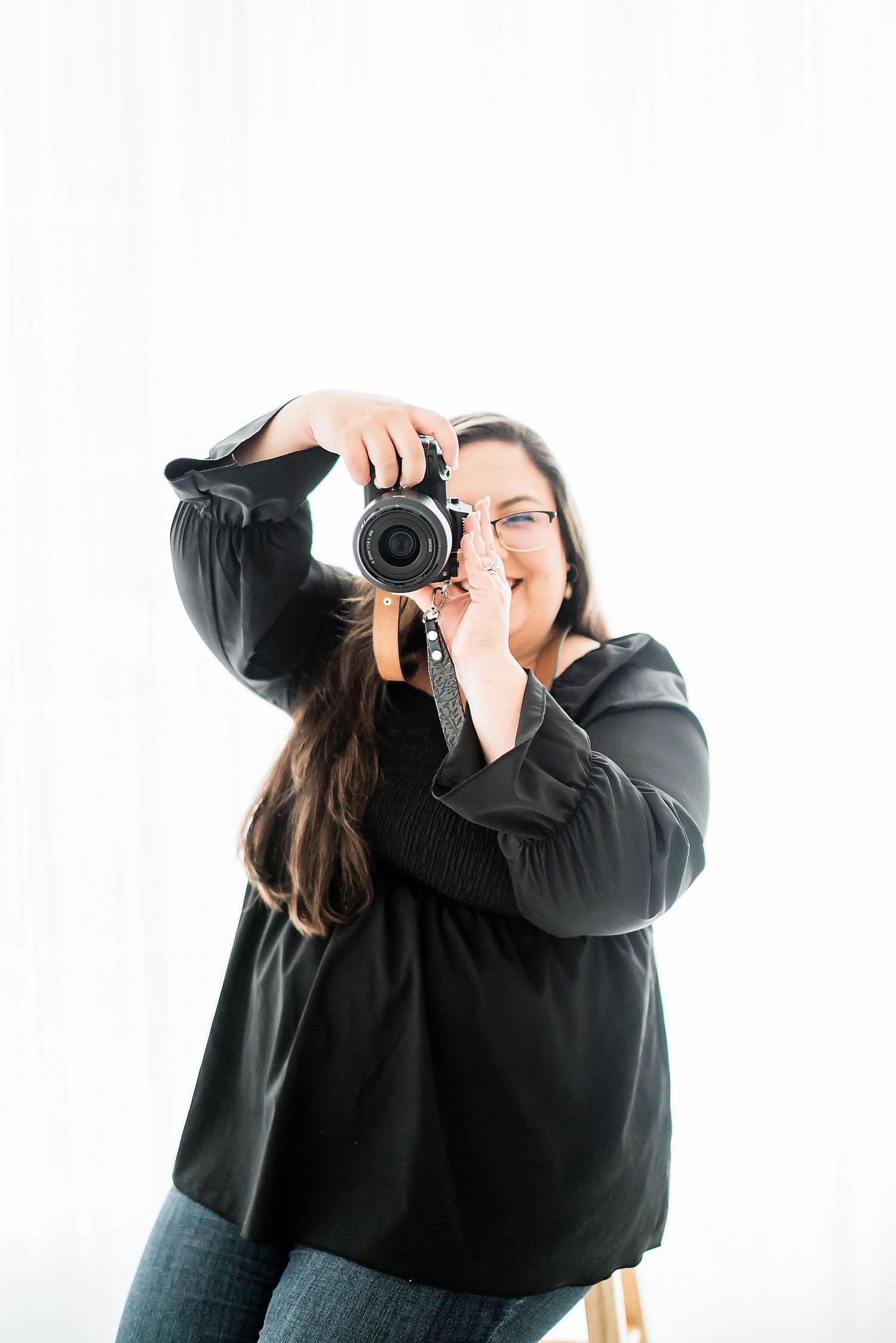 Photographer holding camera and taking photos against white background.