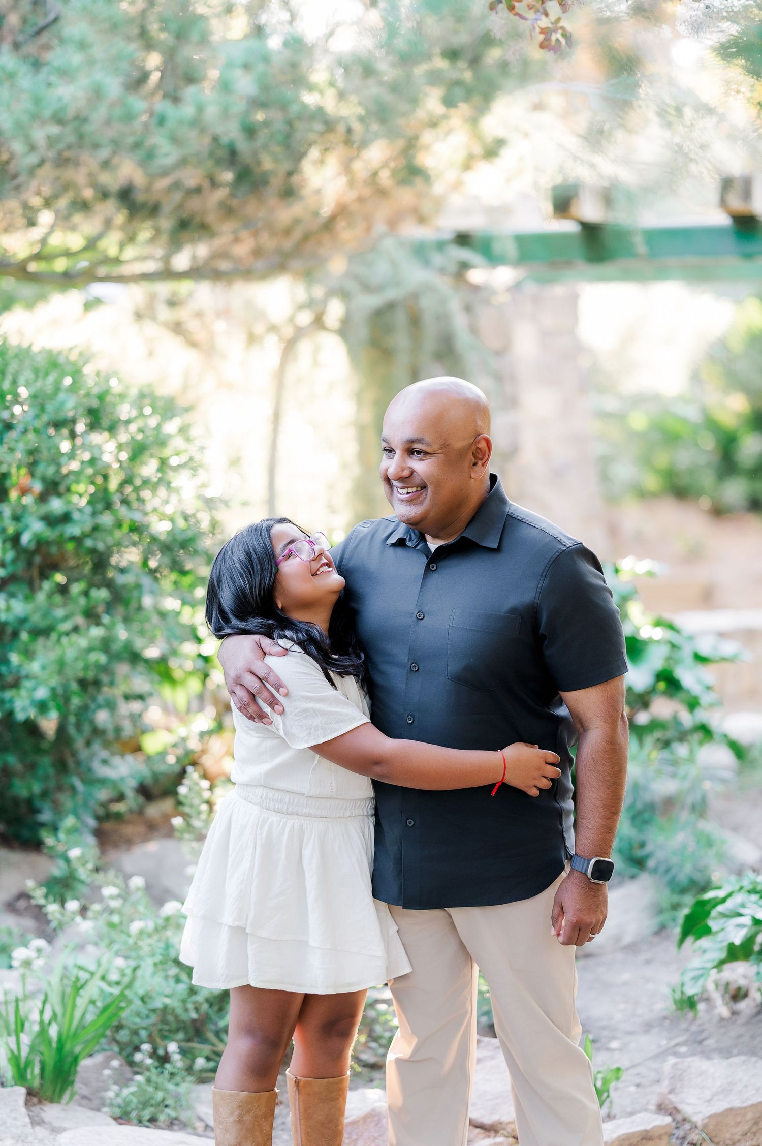 A couple shares tender moments together during an outdoor photoshoot in a garden setting.