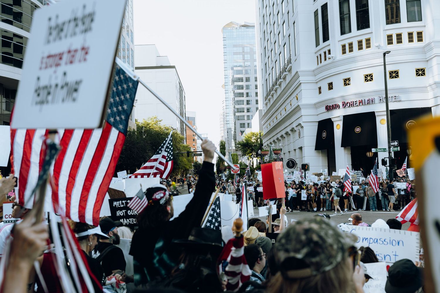 Protesters with American flags gather in urban street during demonstration.