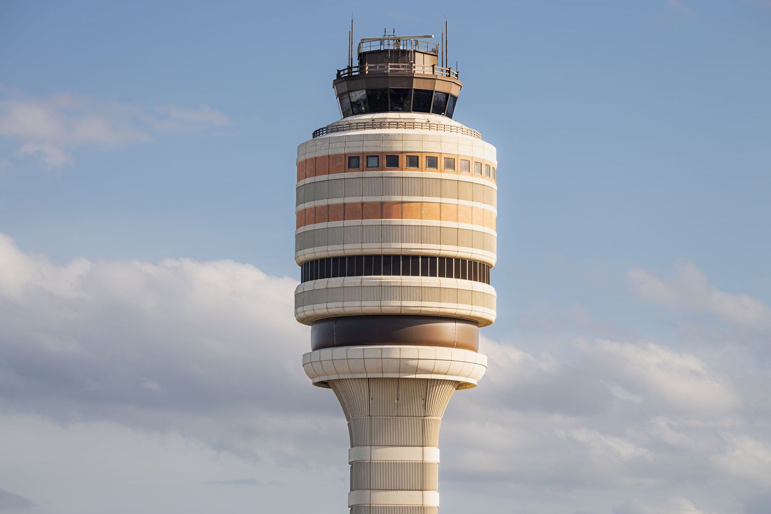 Airport air traffic control tower against a blue sky with clouds at Washington Dulles International Airport.
