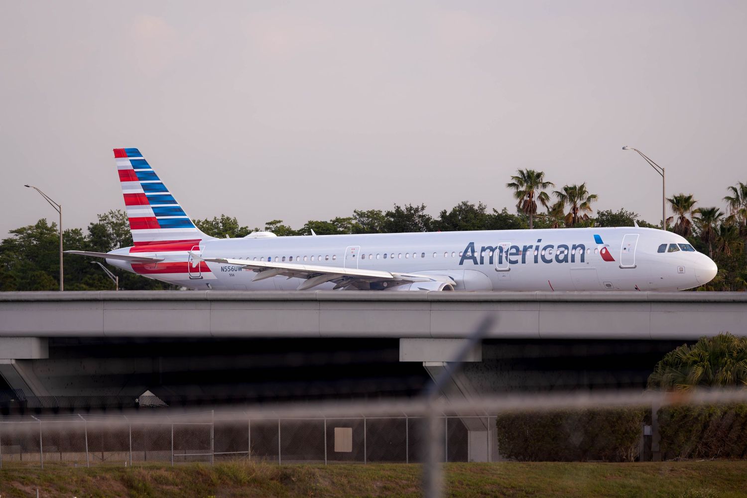 American Airlines Airbus A321 taxiing on runway at Orlando International Airport with palm trees in background.