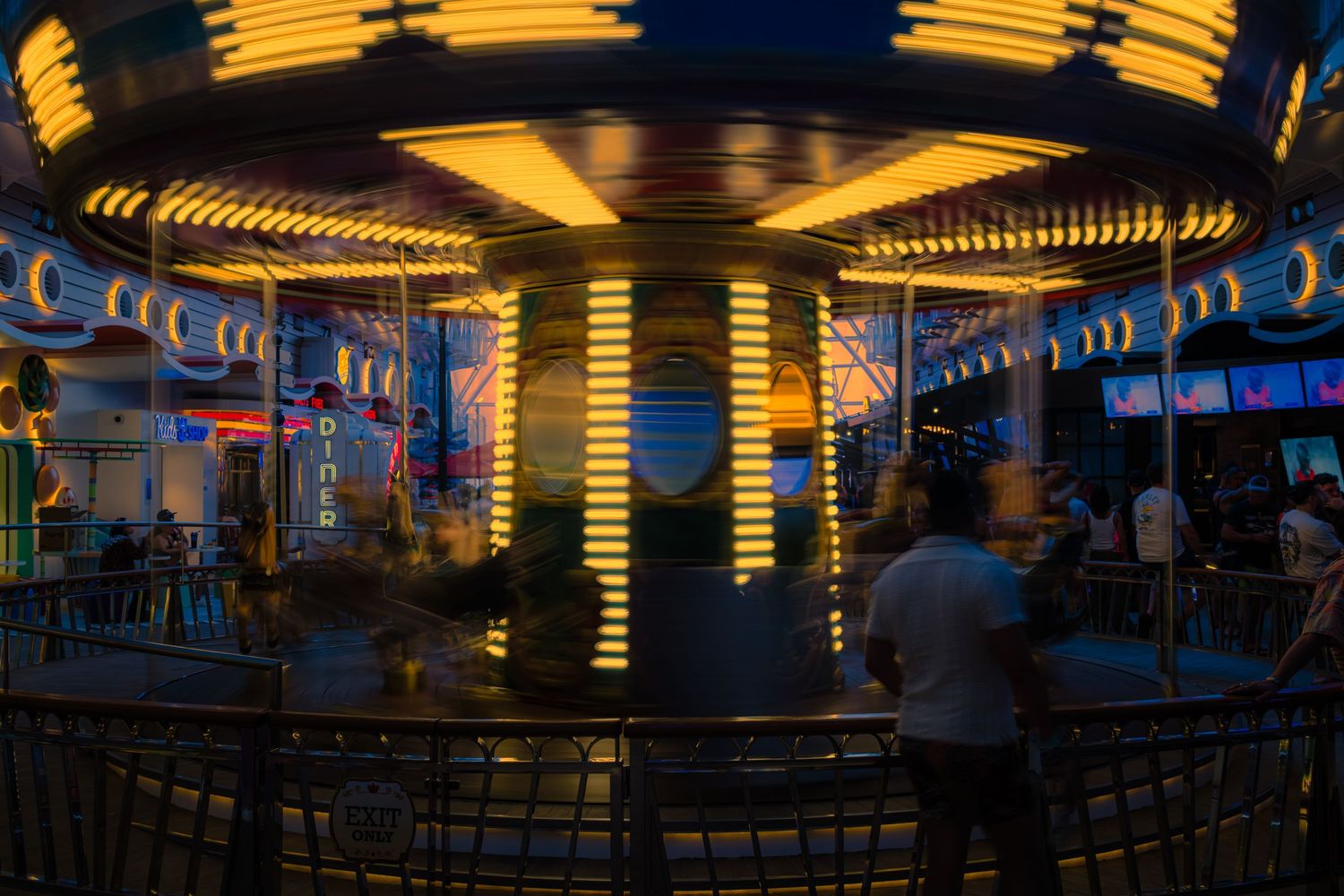 Illuminated carnival ride glows with yellow and blue lights against dark night sky at an amusement park.
