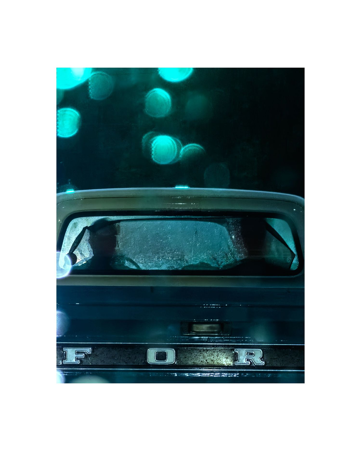 Vintage Ford pickup truck rear view with teal bokeh lights in dark, moody nighttime setting.