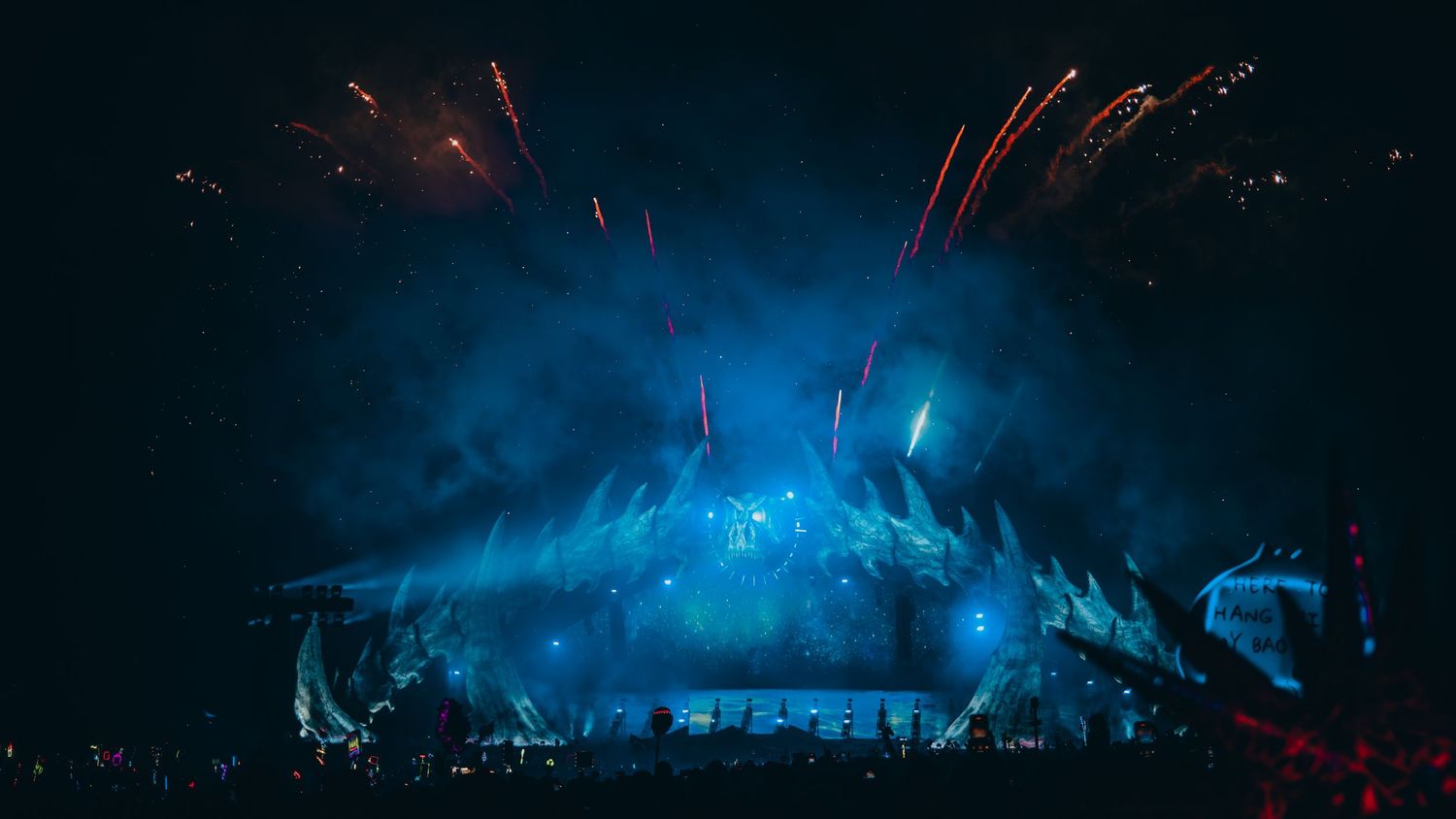 Concert stage illuminated with vibrant blue lights and fog effects creating a dramatic atmosphere during live performance.