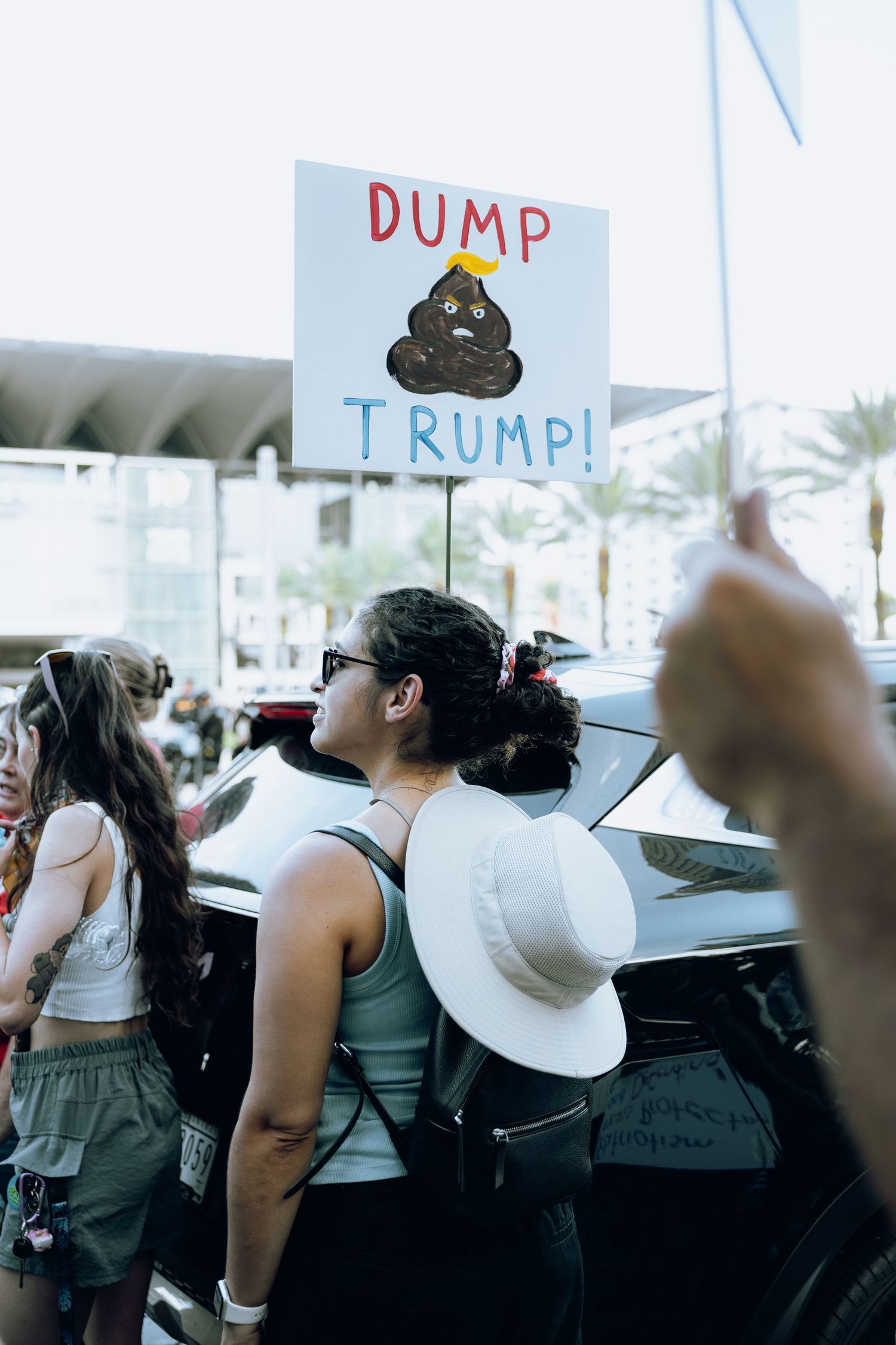 Anti-Trump protest sign held up among crowd of demonstrators in urban setting.