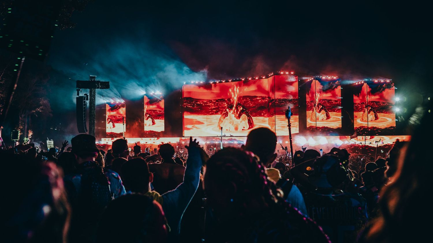 Concert crowd silhouettes against vibrant red stage lighting at a live music performance.