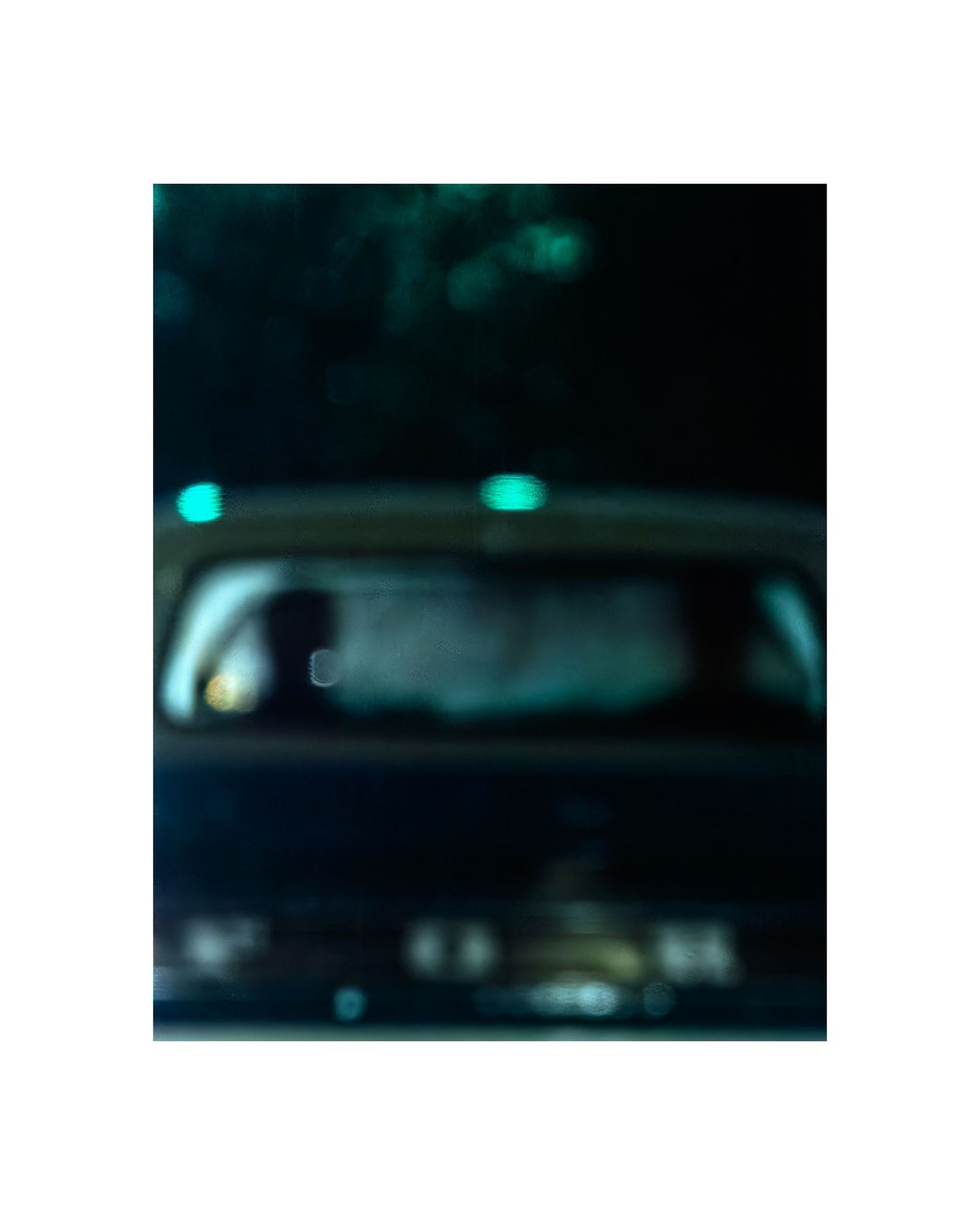Blurry nighttime photo of a dark car interior with a silhouetted figure and teal lights glowing on the roof.