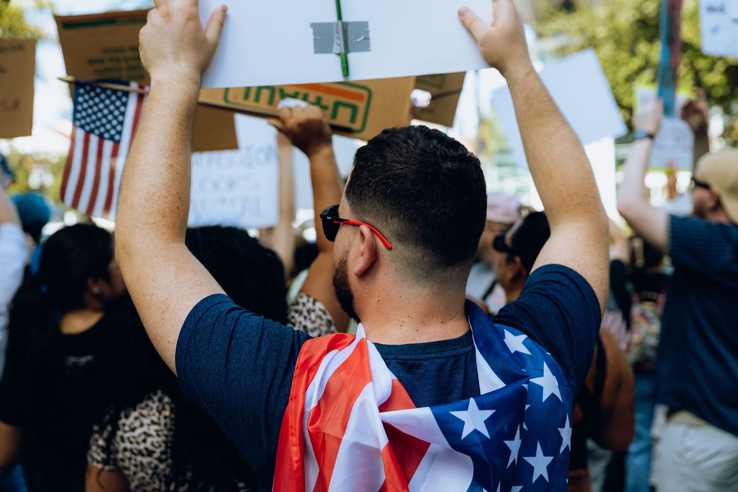 Protester draped in American flag raises hands during demonstration.