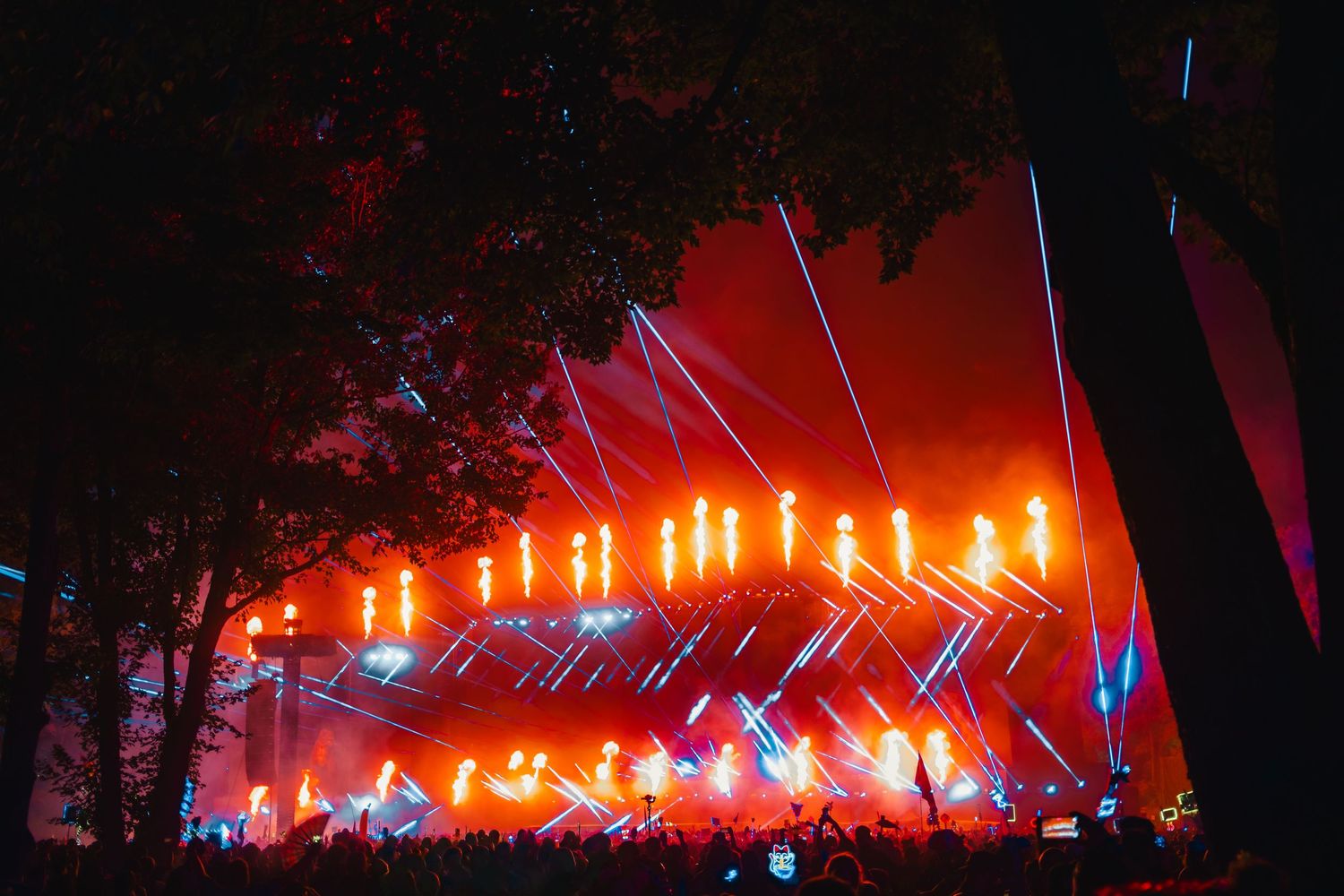 Concert stage illuminated with vibrant red lights and smoke effects creating a dramatic atmosphere during a live performance.