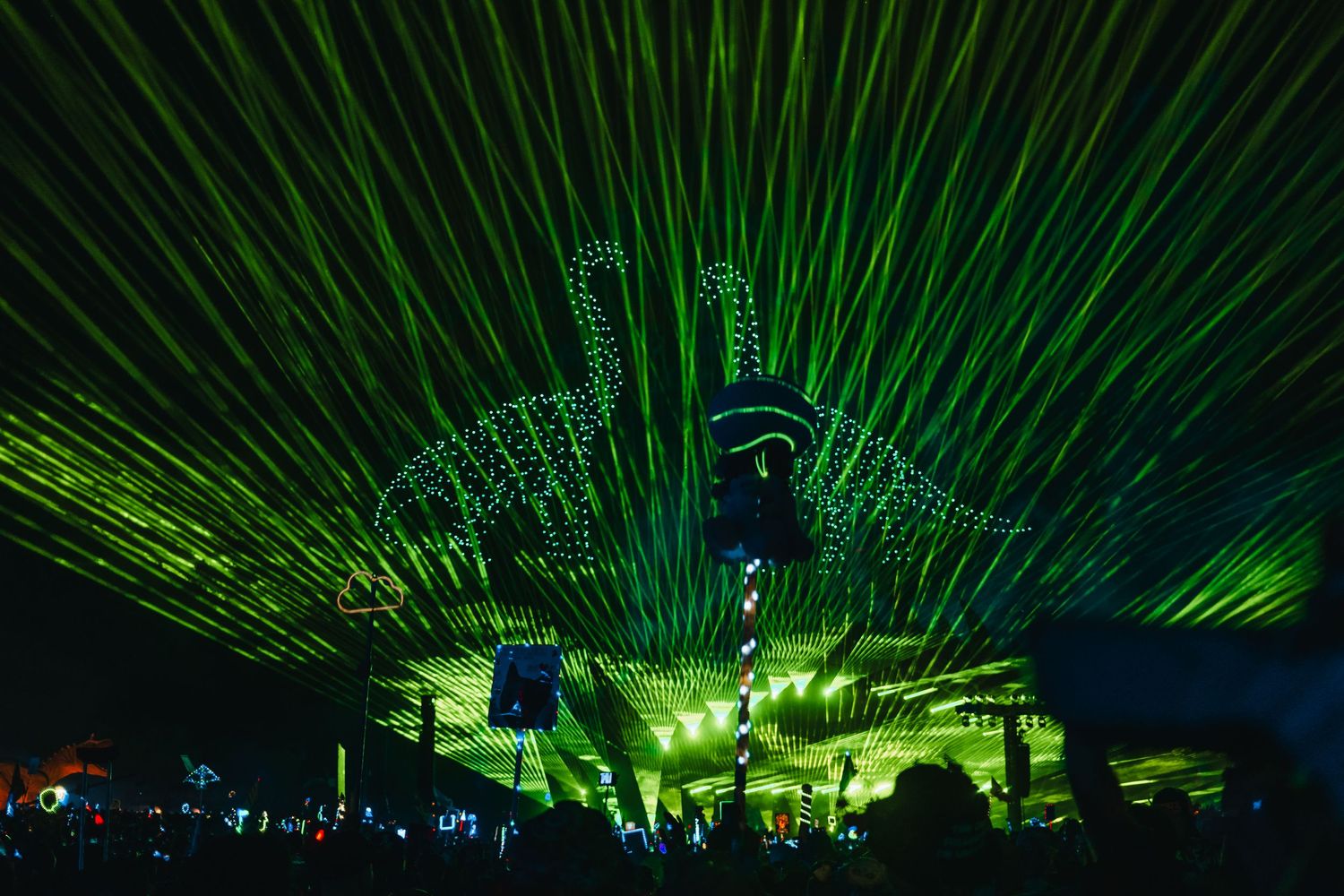 Green laser beams illuminate a dark concert venue with spectacular light show effects creating an immersive atmosphere.