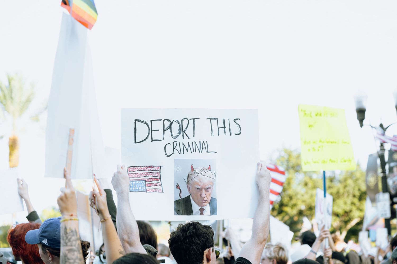 Protesters hold signs during political demonstration outdoors.