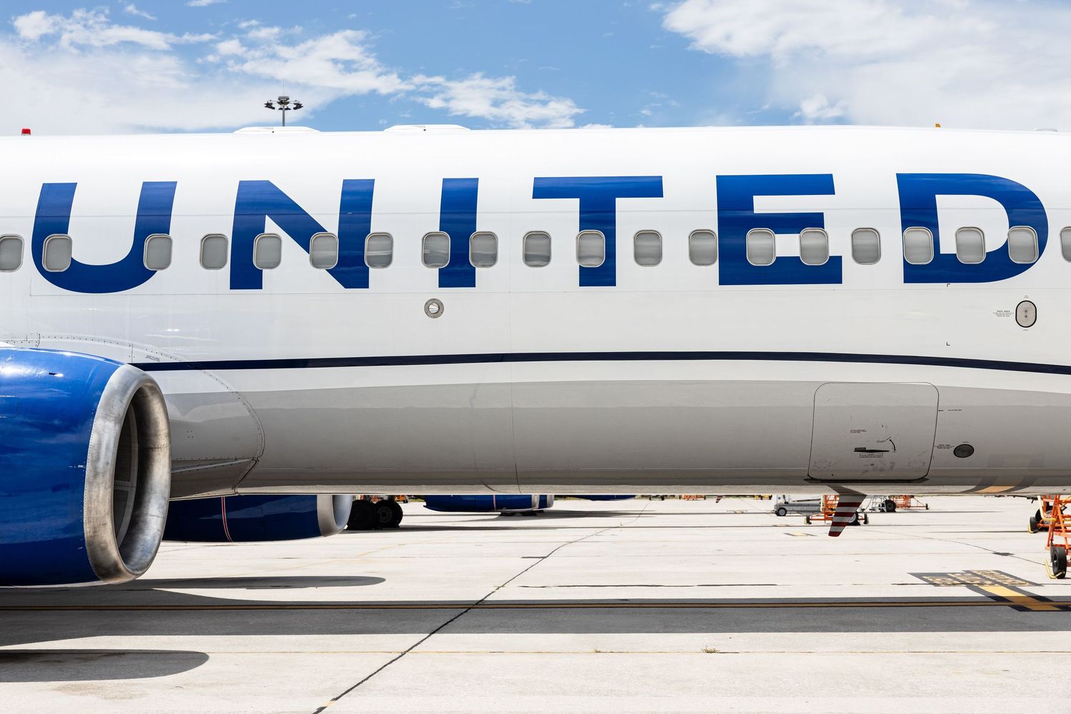 Close-up of a United Airlines aircraft fuselage with blue engine and bold UNITED branding on the tarmac.