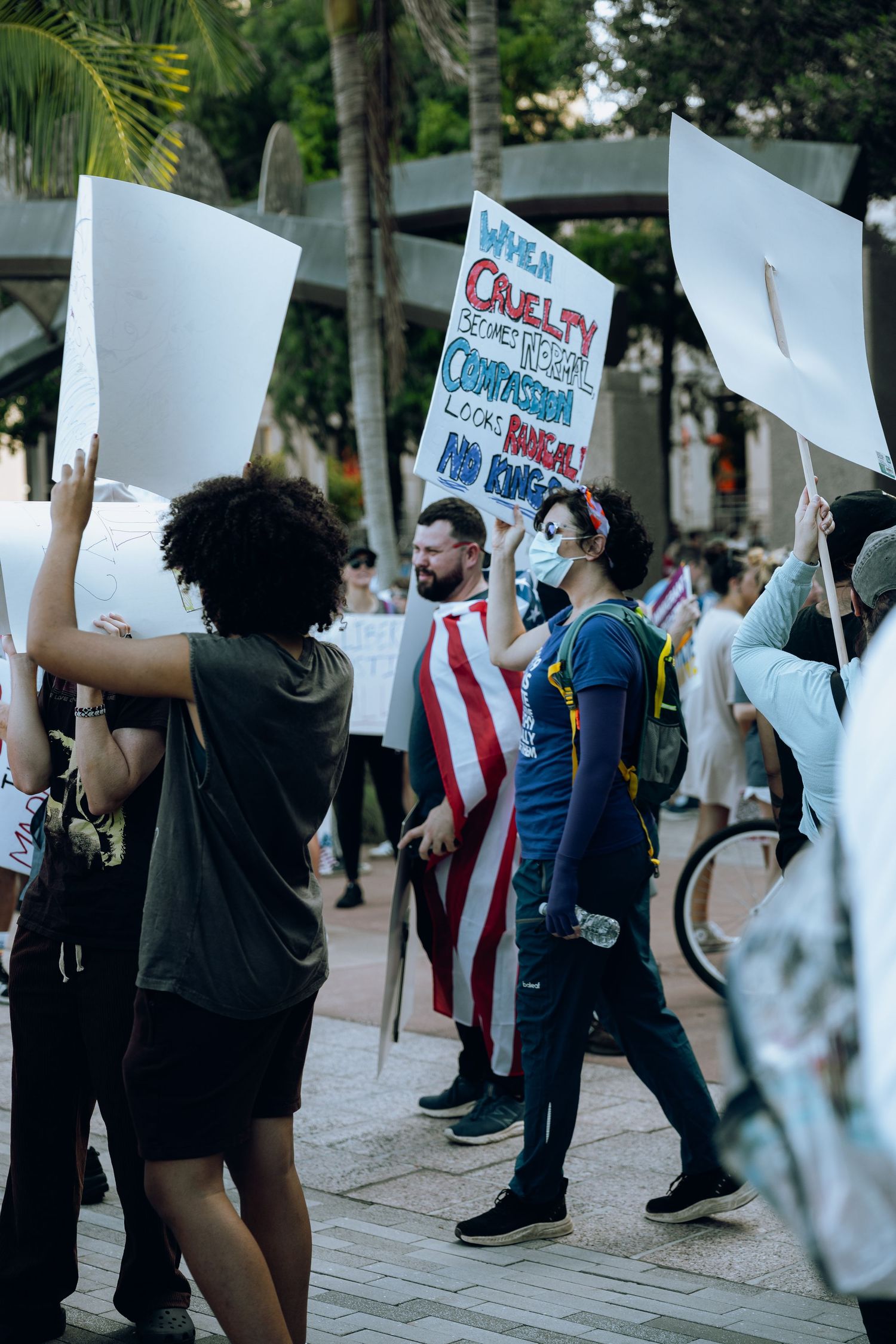 Protesters holding white signs gather on a sidewalk for a peaceful demonstration.