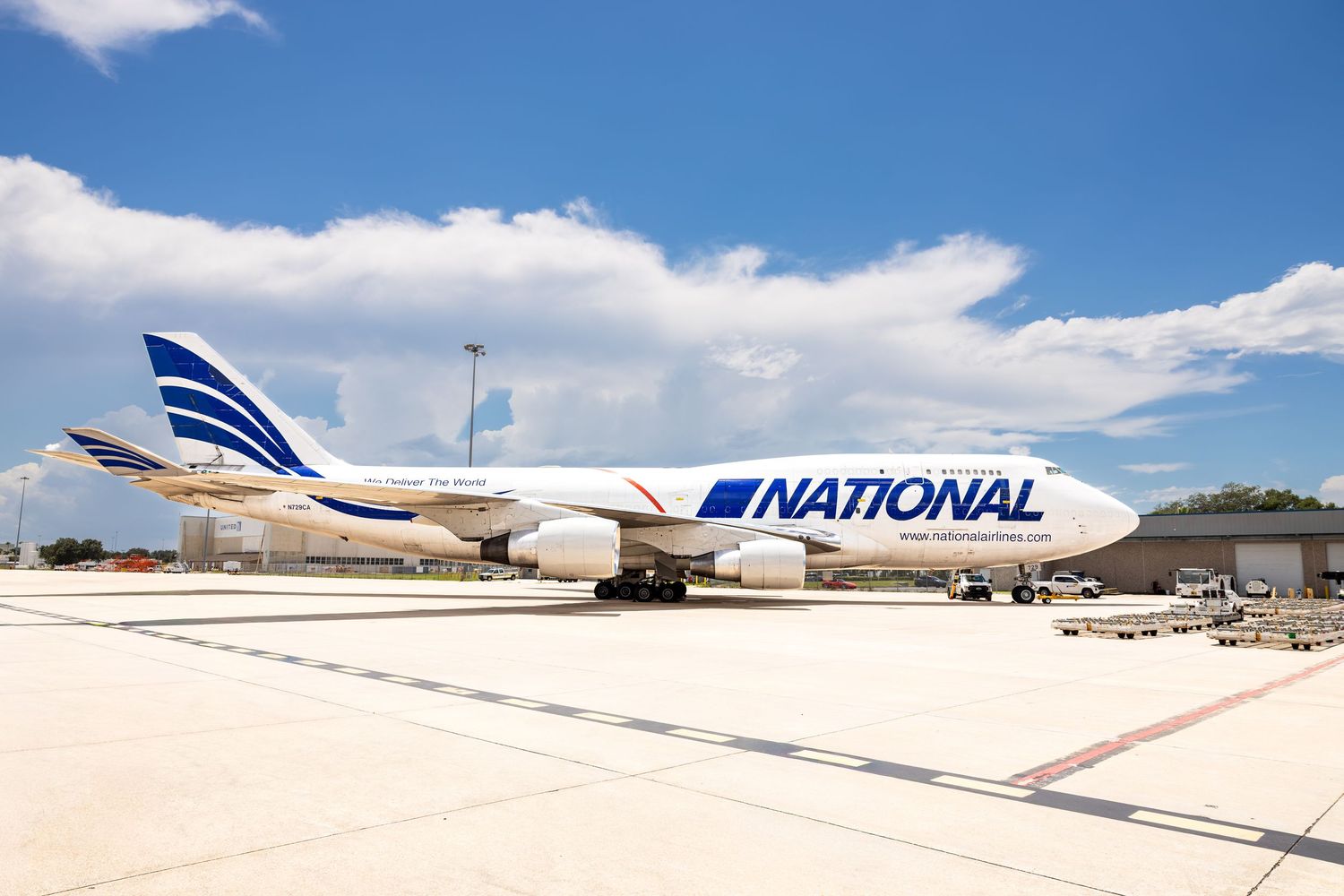 National Airlines Boeing 747 cargo aircraft parked on sunny airport tarmac with blue sky and white clouds.
