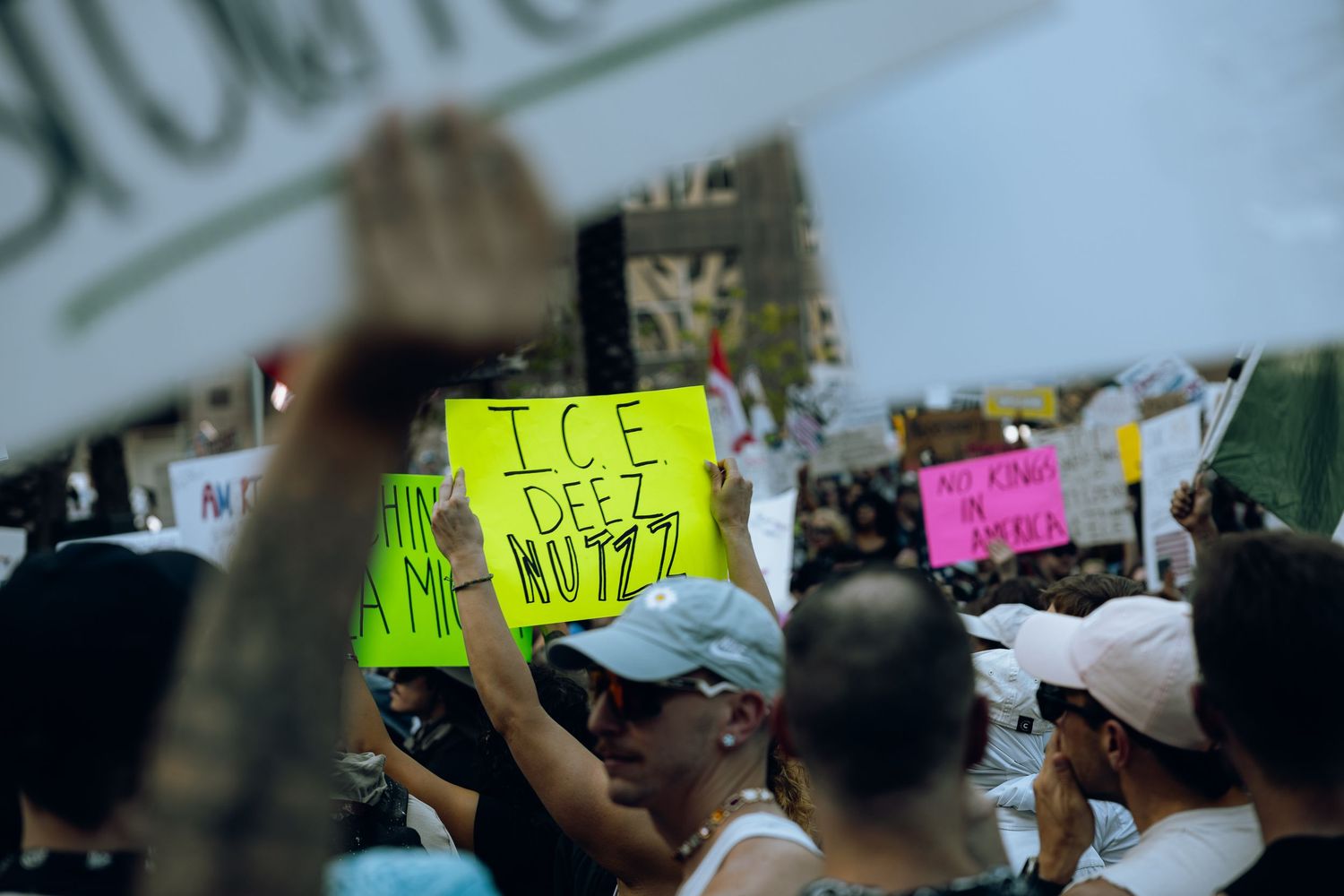 Neon yellow protest sign about ICE held up among crowd of demonstrators.
