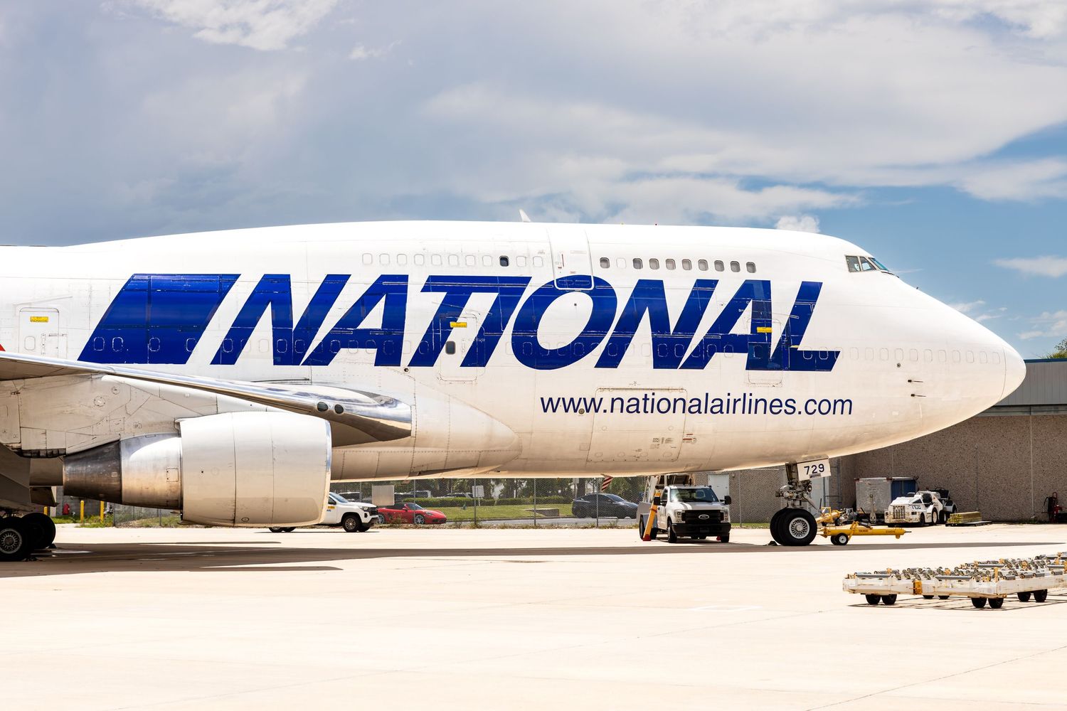 National Airlines Boeing 747 cargo plane parked on tarmac at airport, featuring bold blue logo on white fuselage.