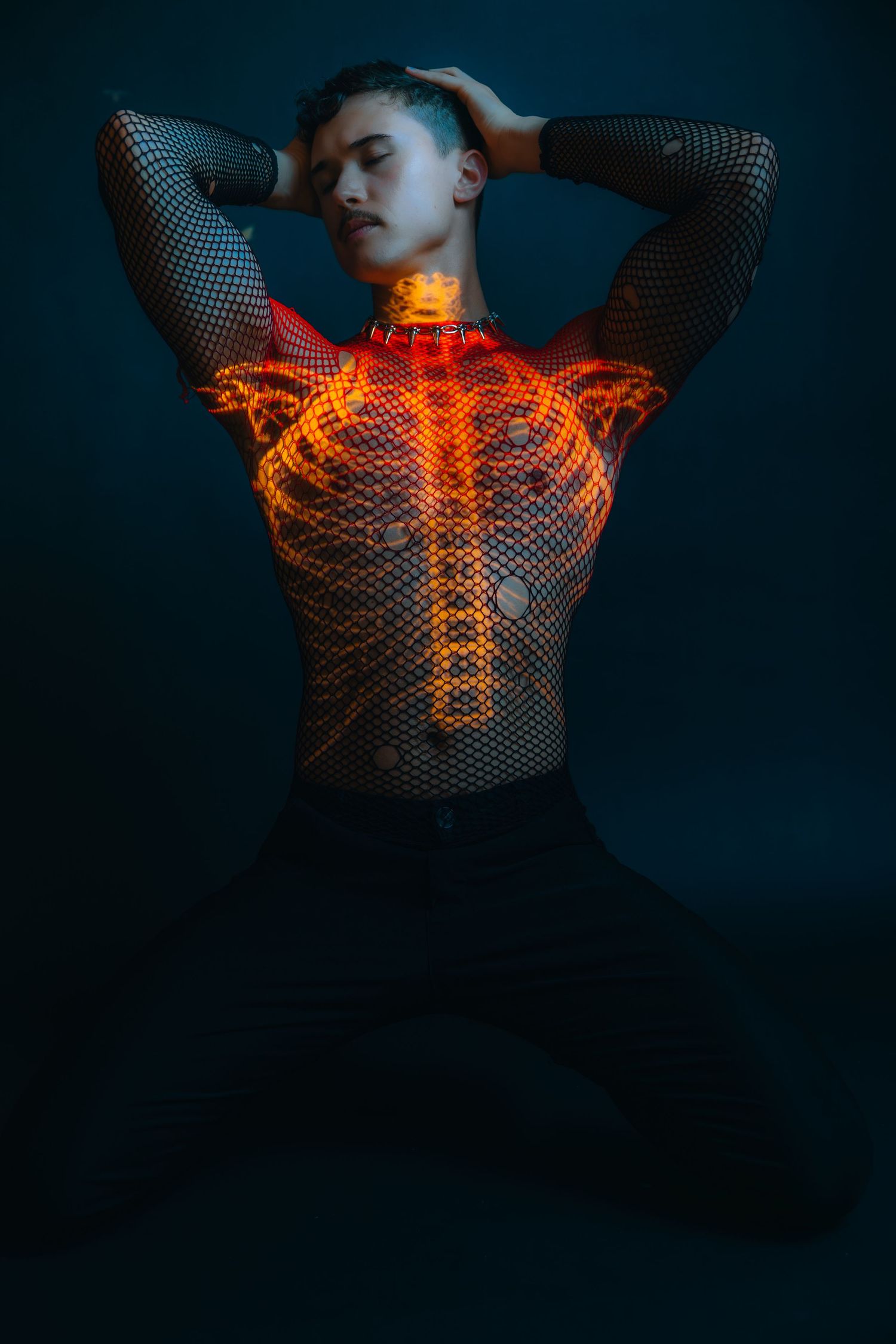 Person wearing mesh top with glowing skeleton projection on dark background, artistic body art photography.