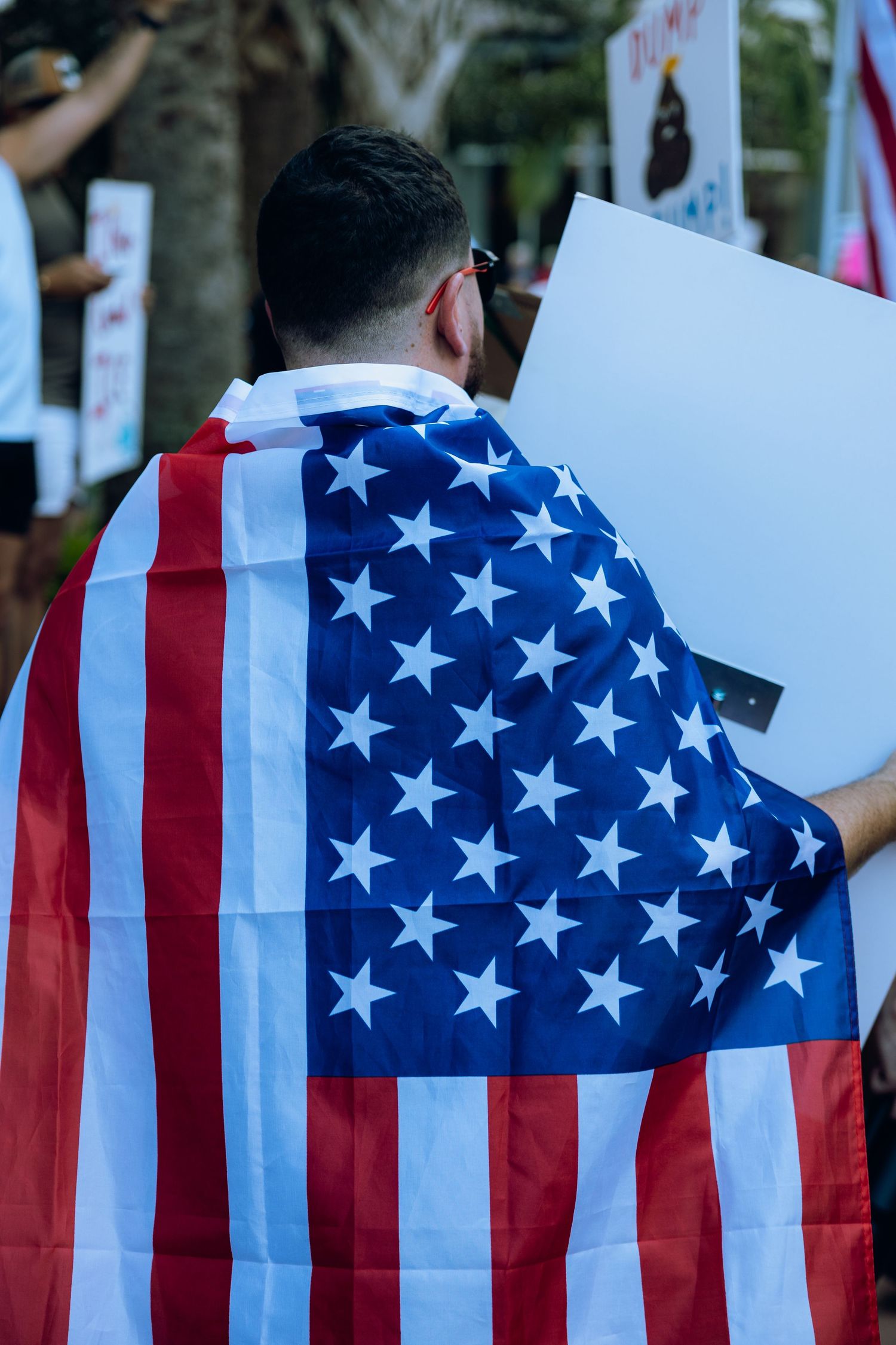 A protester wrapped in an American flag holds a sign during a demonstration.