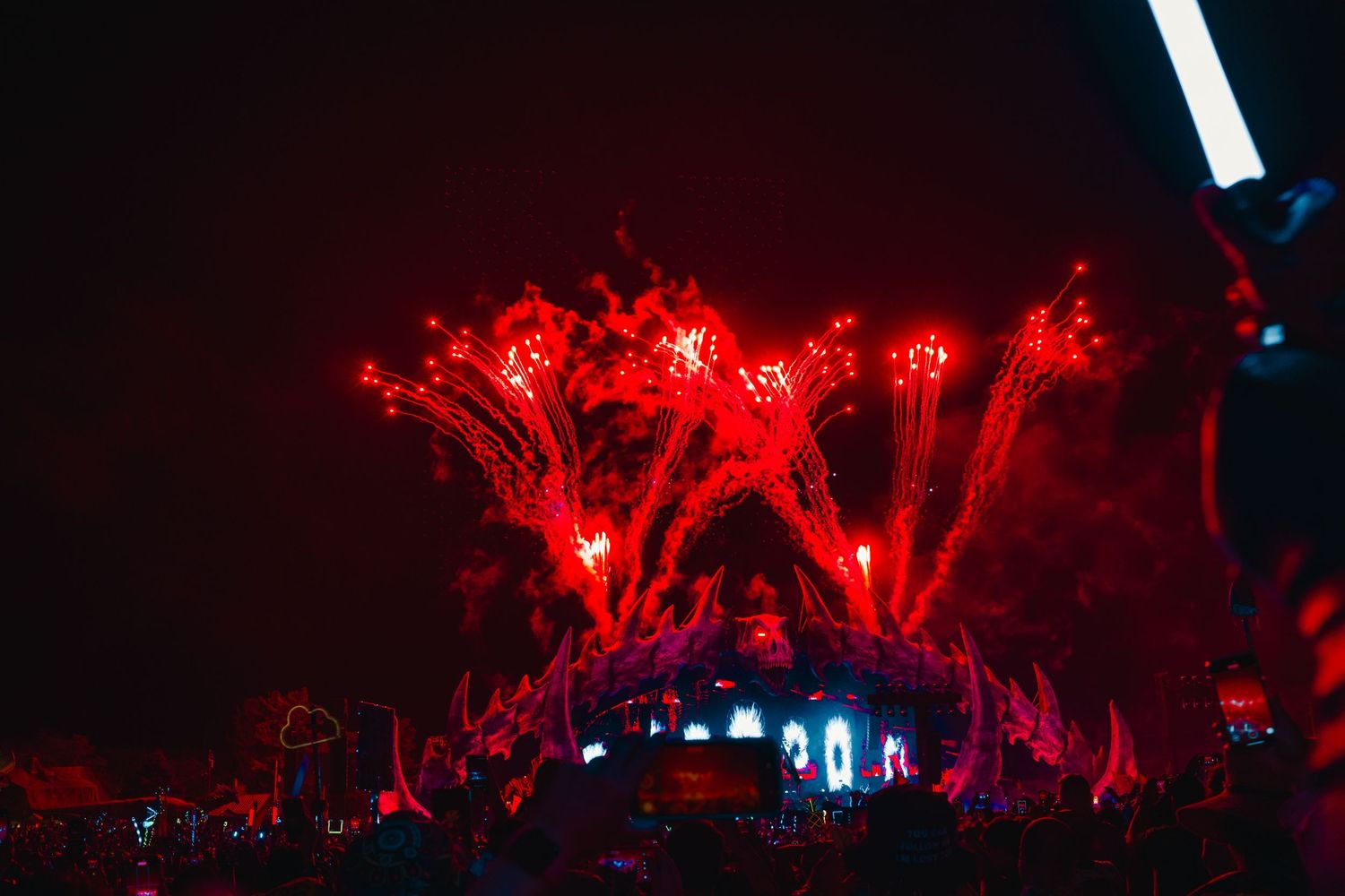 Red fireworks illuminate the night sky over a dark landscape during an outdoor celebration event.