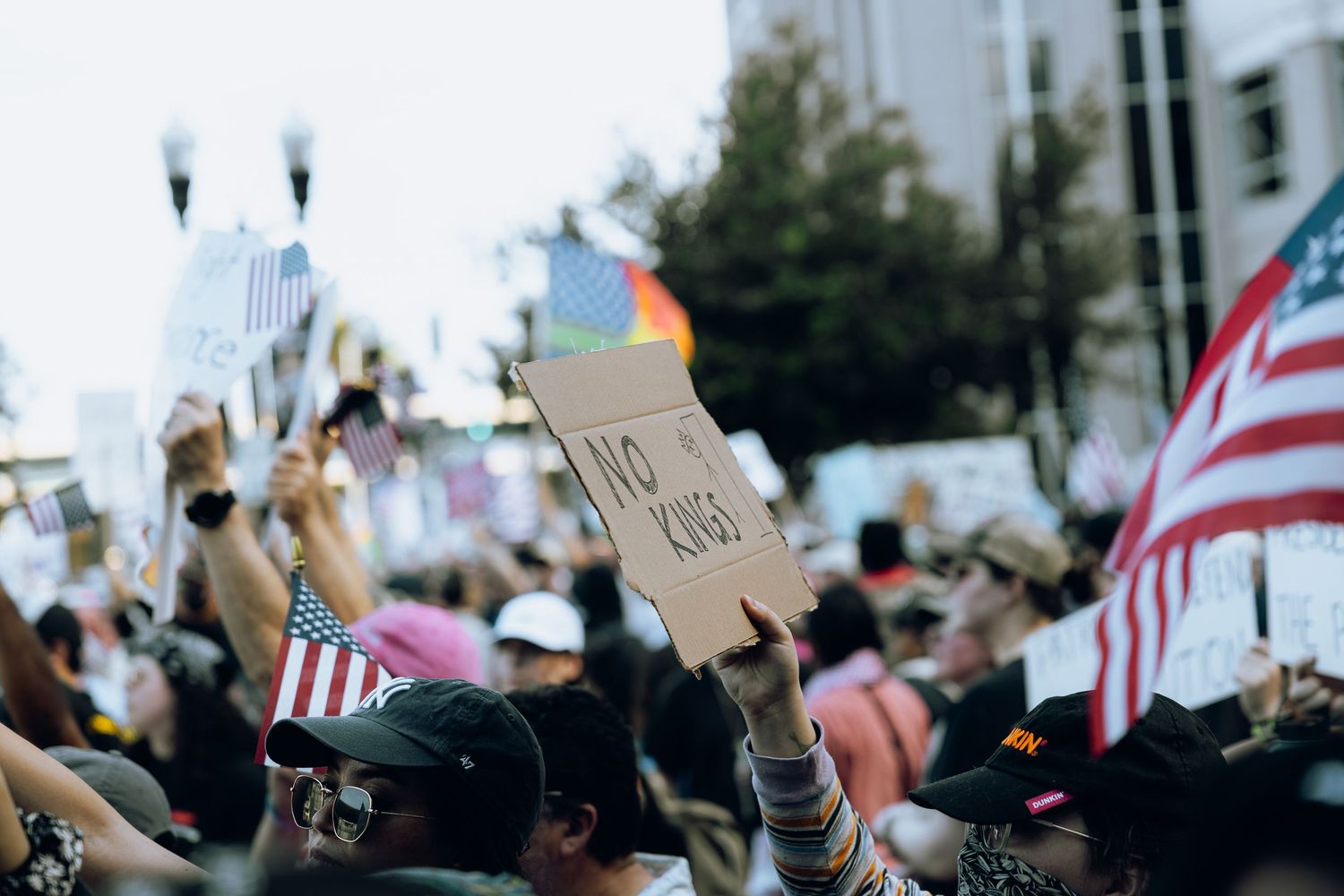 Protesters hold American flags and signs high in the air at a peaceful demonstration.