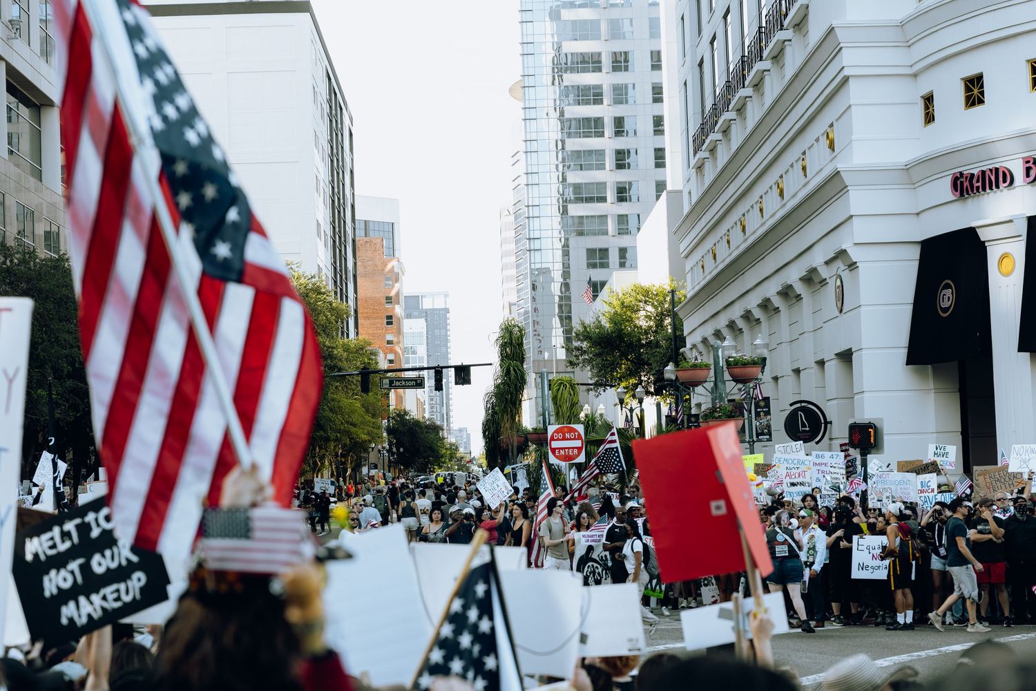 American flags wave among crowd of protesters on city street.