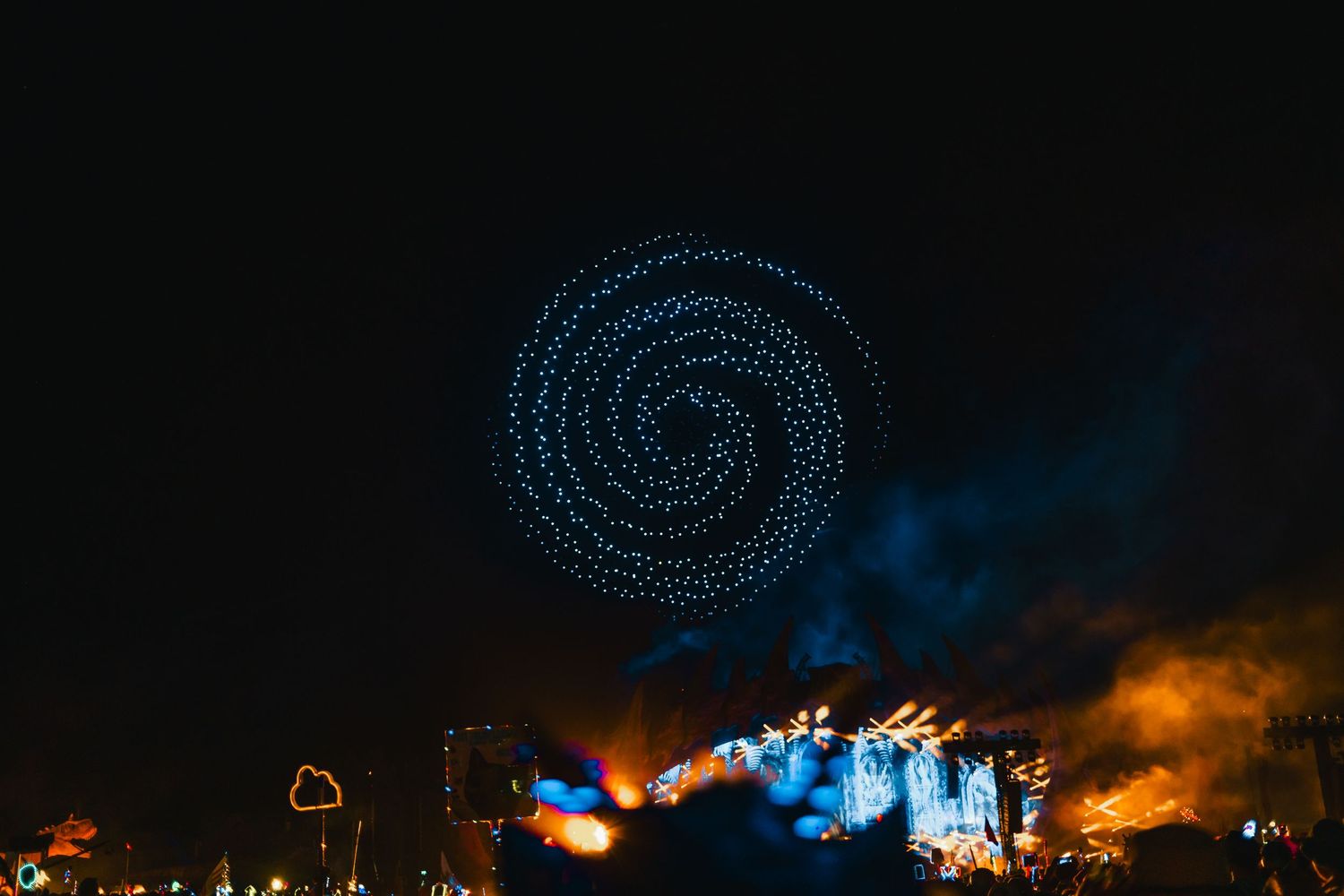 Long exposure night photography captures spinning light trails creating circular patterns against dark background.