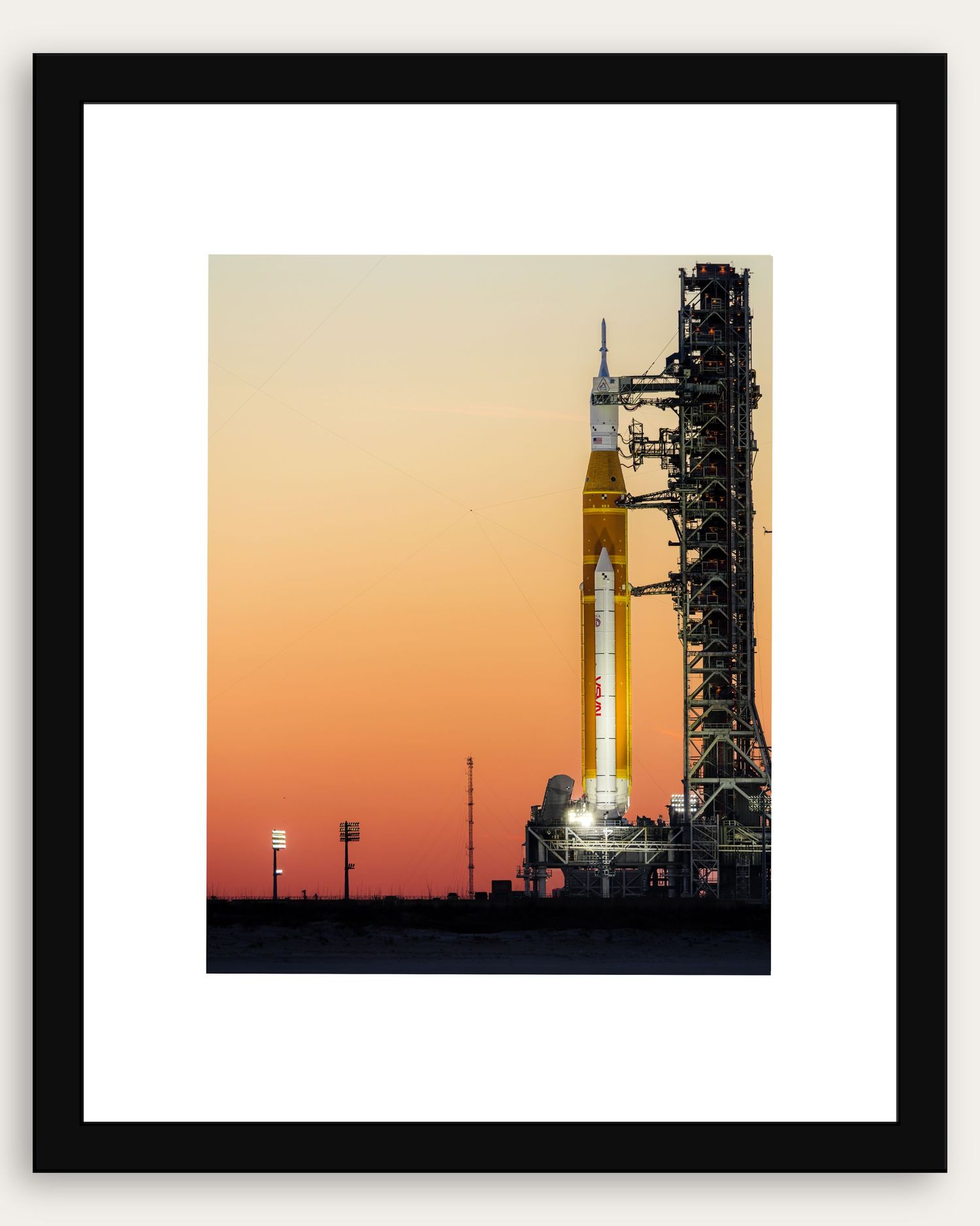 NASA Space Launch System rocket on launch pad at sunset with orange sky, framed print.