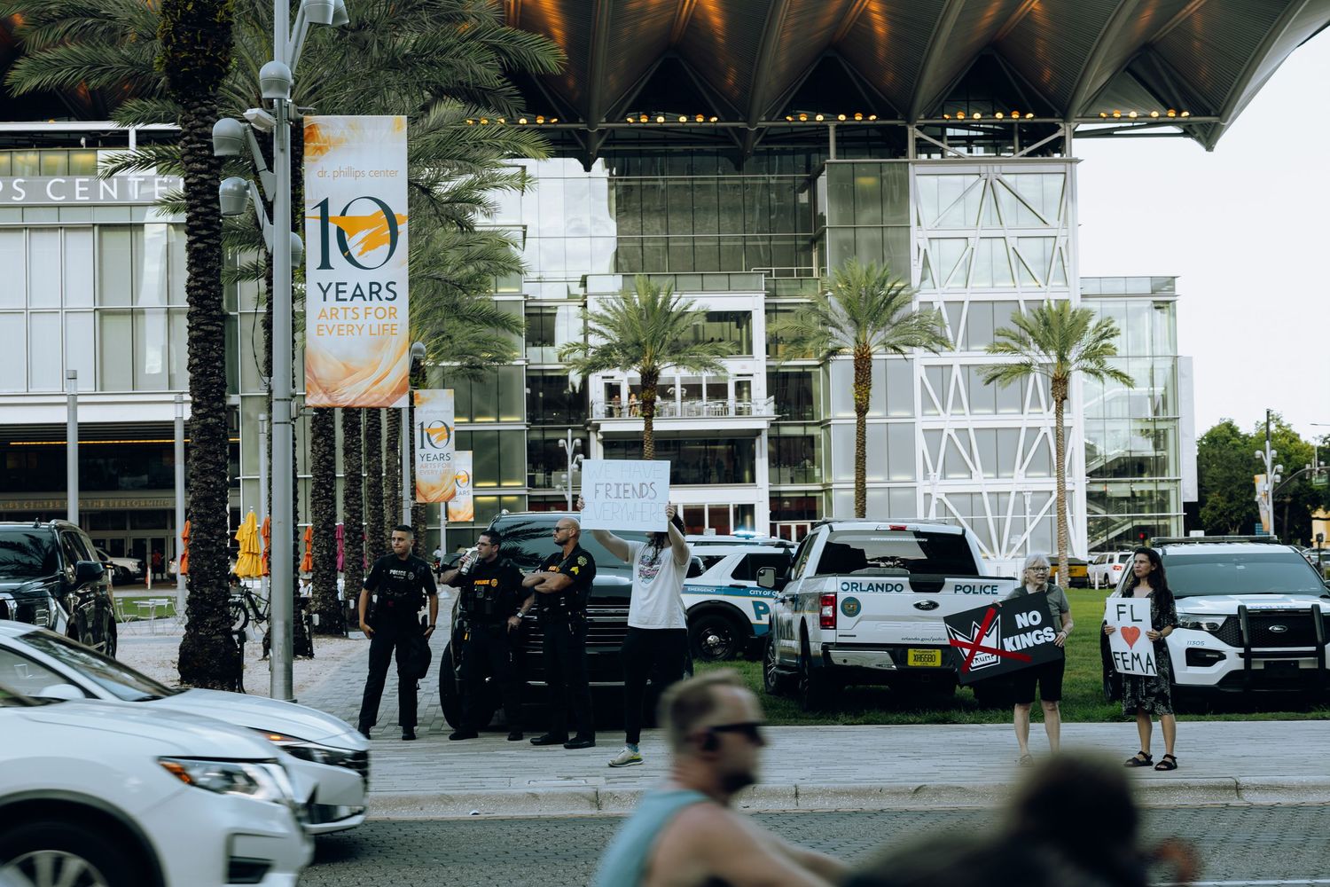 Police vehicles and officers stationed outside modern building entrance.