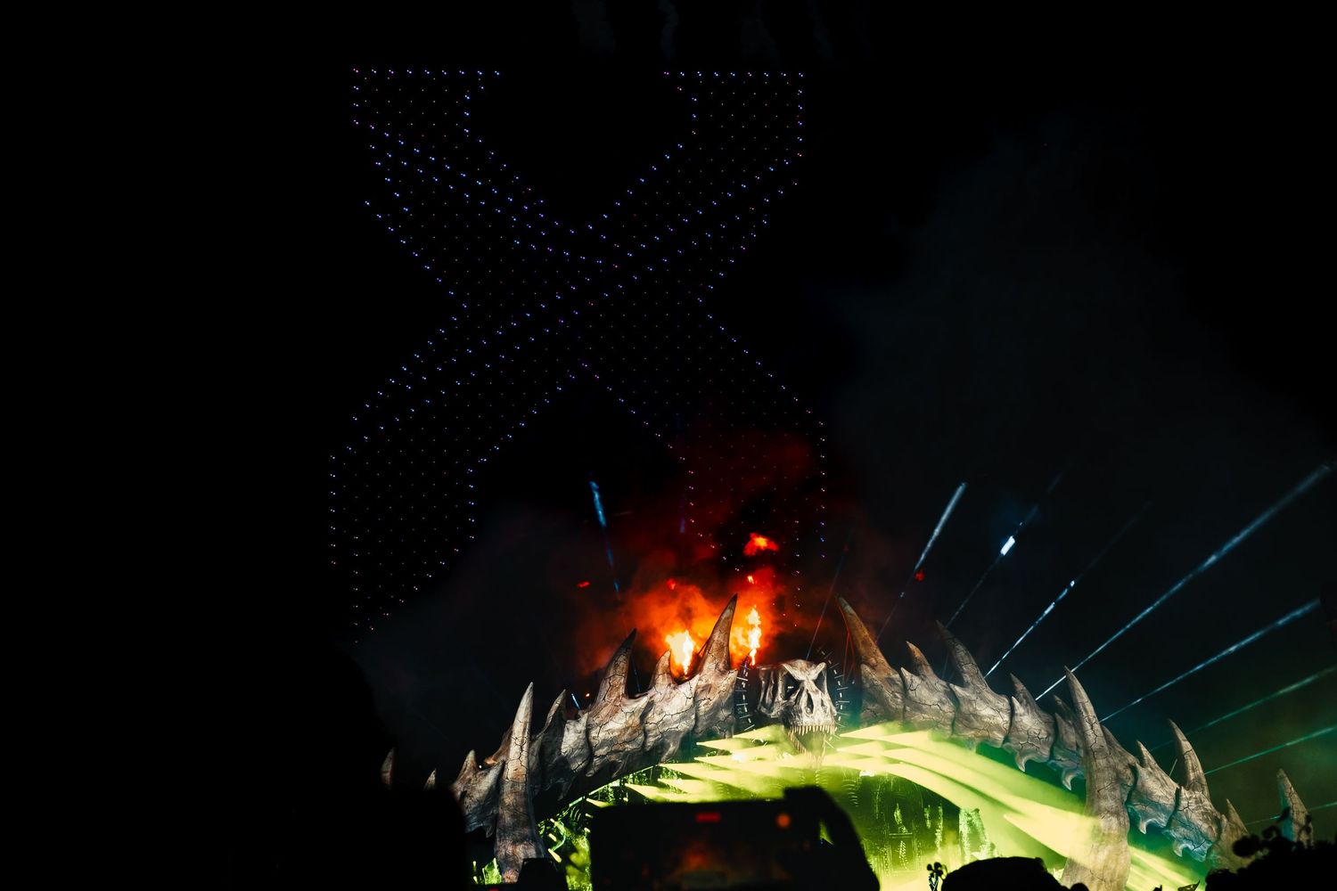 Dramatic concert stage lighting with red and blue beams illuminating a dark venue through smoke and haze.