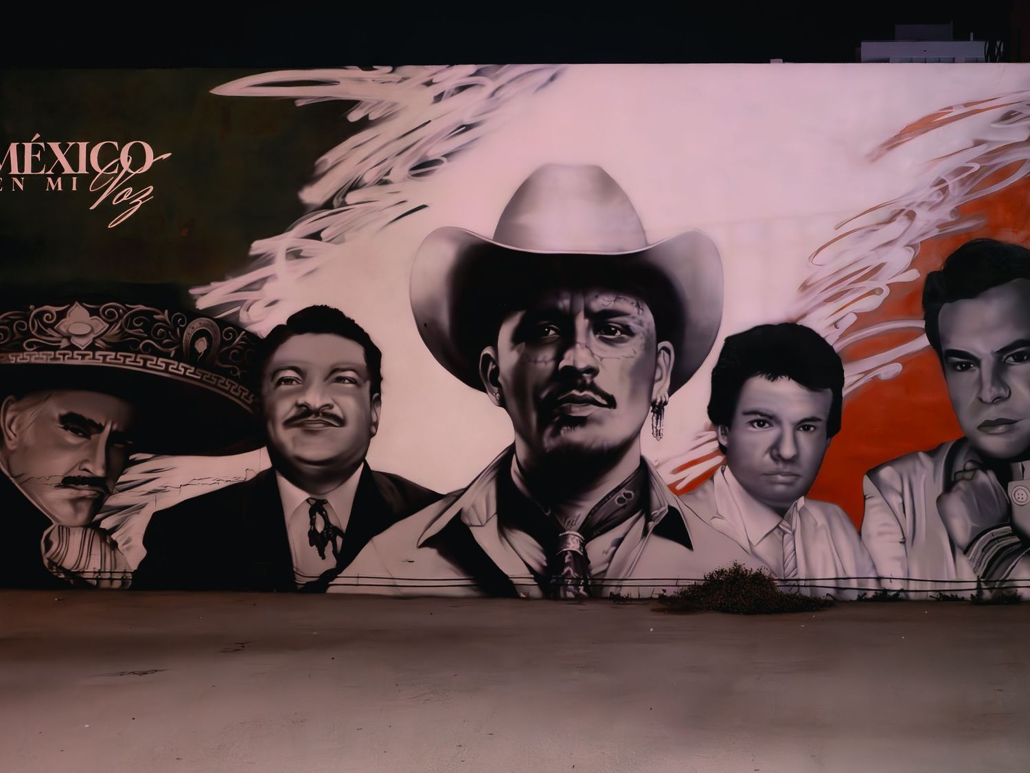 A black and white painted mural on a wall shows vintage-style portraits against an orange and black background.
