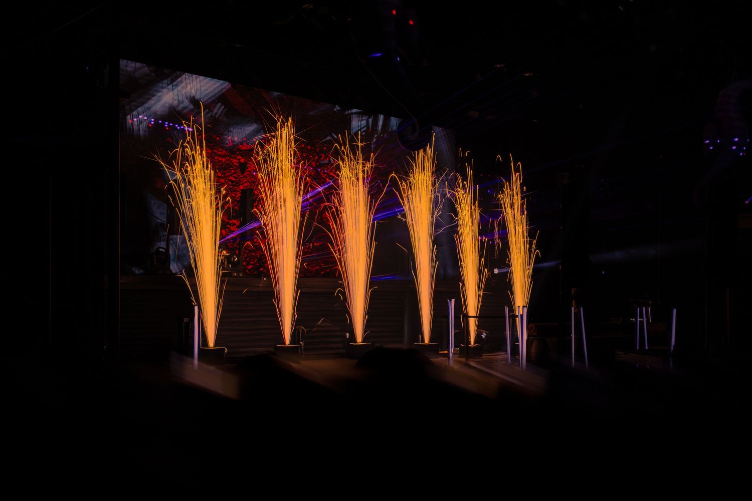 Multiple bright orange firework fountains shooting upward in sequence against a dark night sky background.