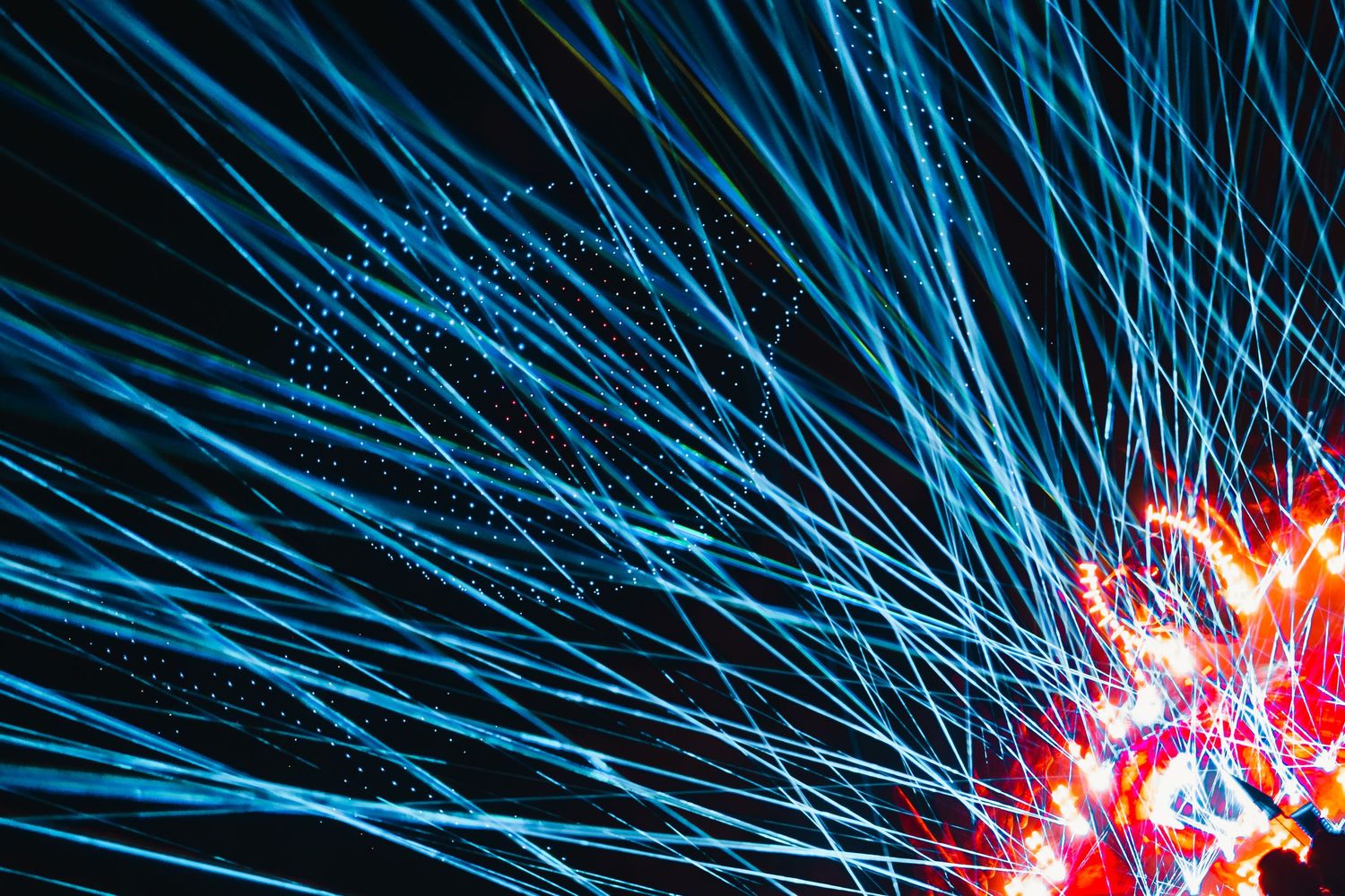 Abstract light trails in blue and pink colors create dynamic patterns against a dark background.