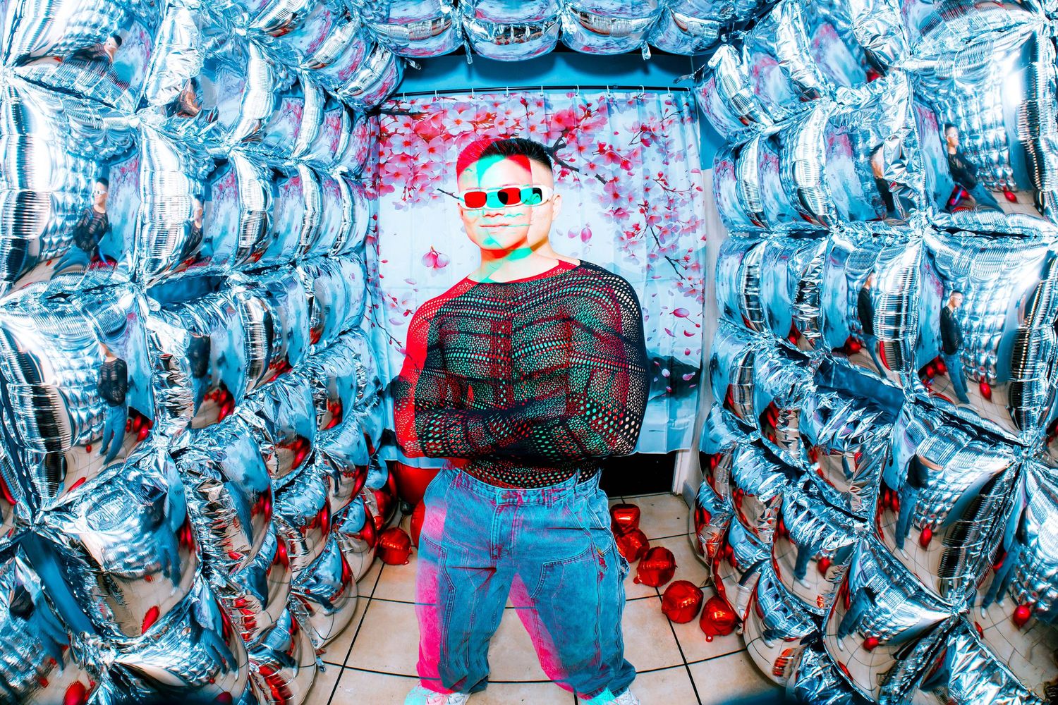 Person in 3D glasses poses in a tunnel of silver balloons with a red and blue chromatic aberration effect.