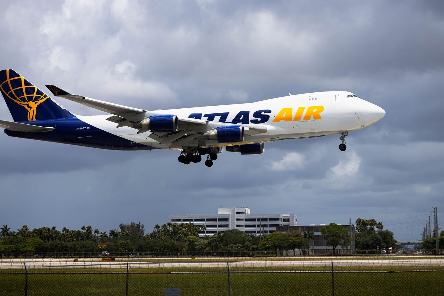 Atlas Air Boeing 747 cargo plane landing at airport with cloudy sky in background.