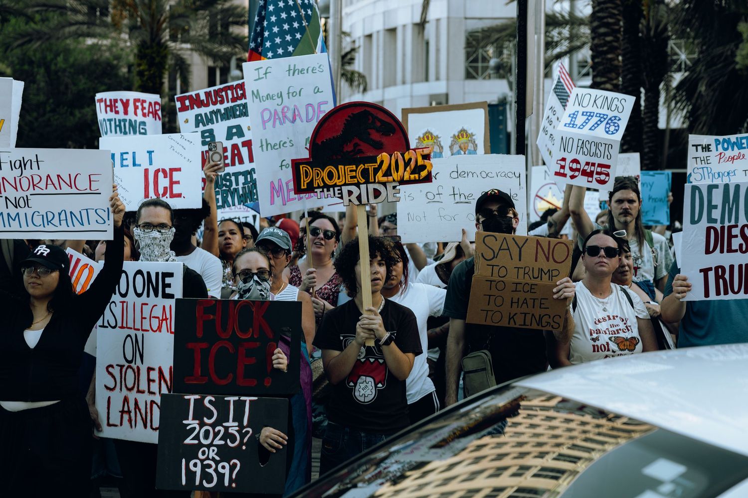 Large crowd of demonstrators with protest signs gather on a city street during a social justice rally.