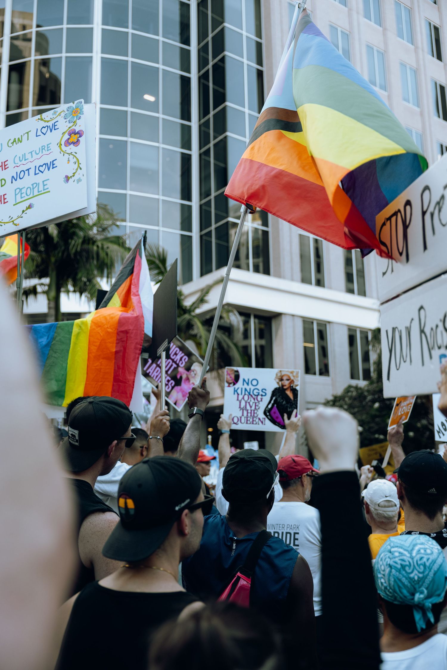 Protesters wave rainbow flags and hold signs during an LGBTQ+ rights demonstration.