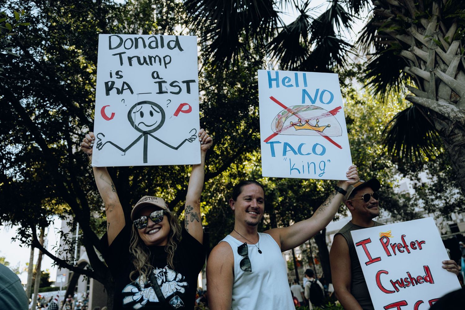 Protesters holding handmade signs at an outdoor demonstration.